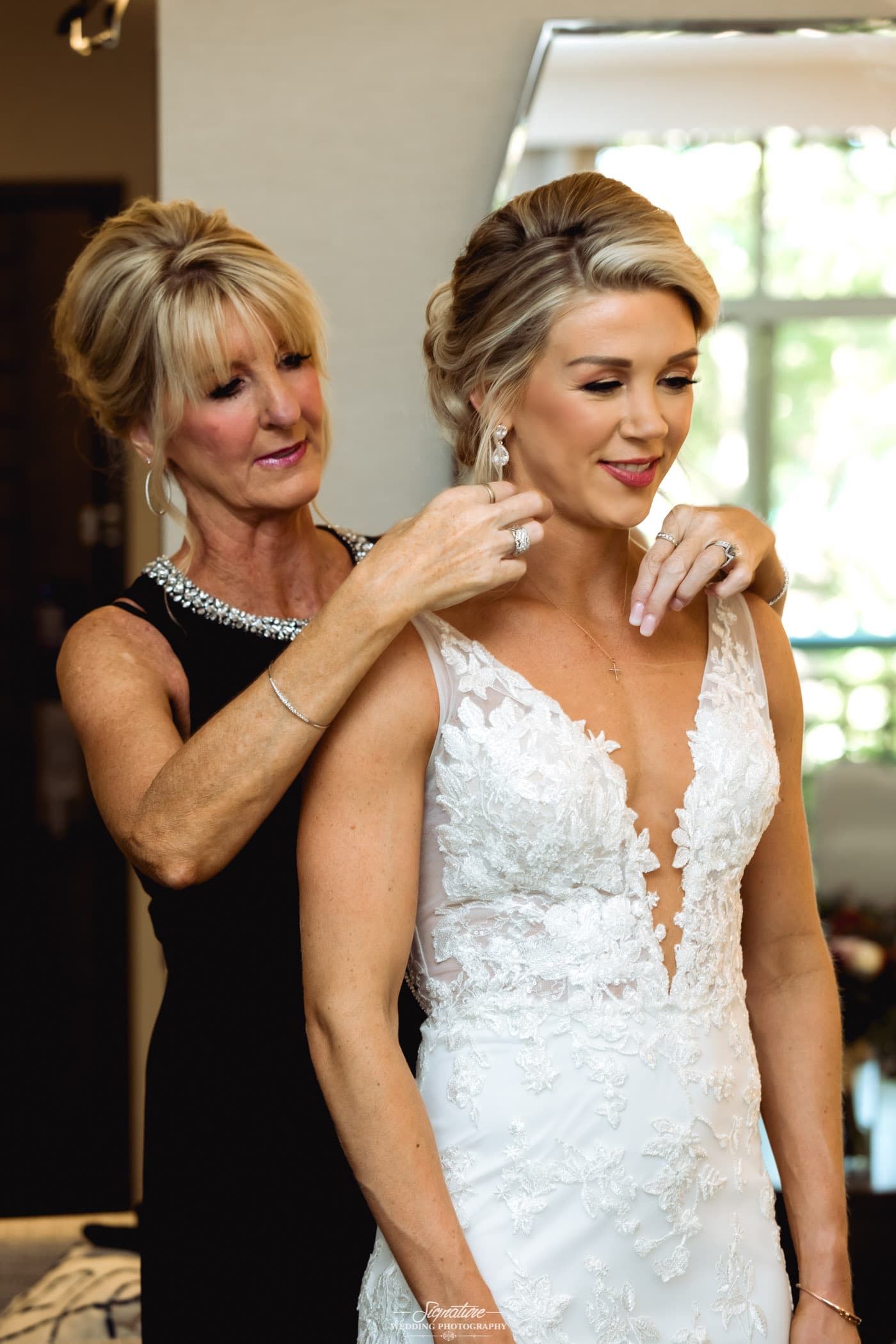 Mom fixing bride's earrings from over shoulder