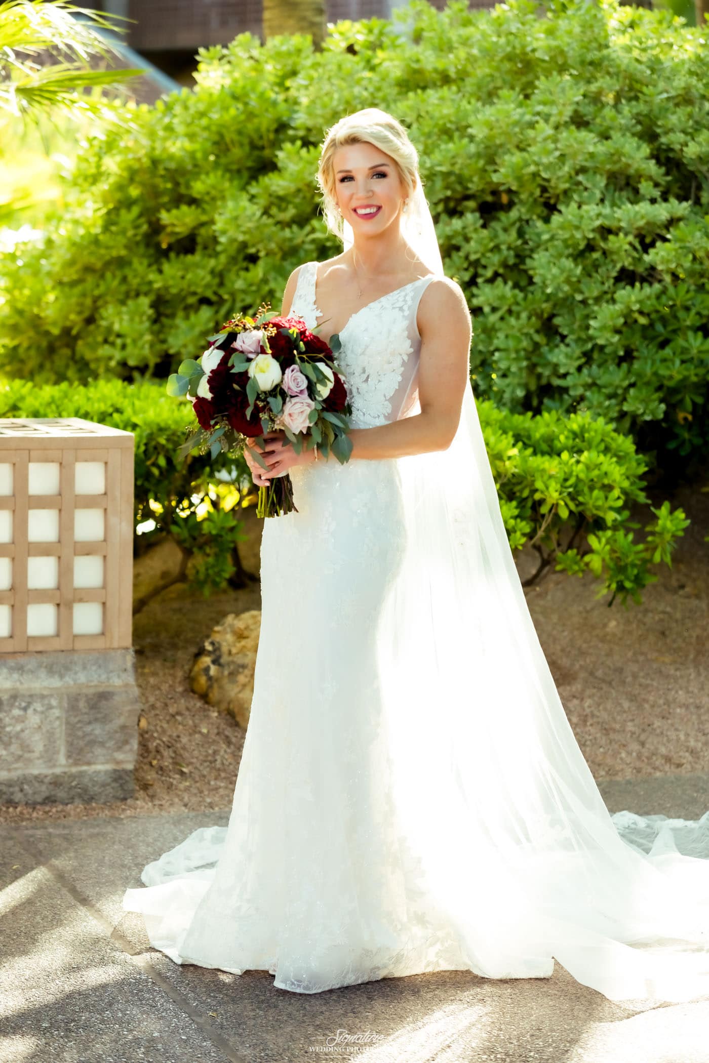 Bride holding bouquet smiling at camera outside