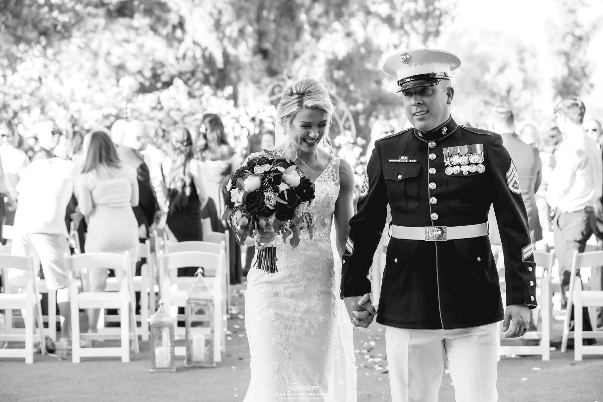 Bride and groom holding hands walking down isle black and white