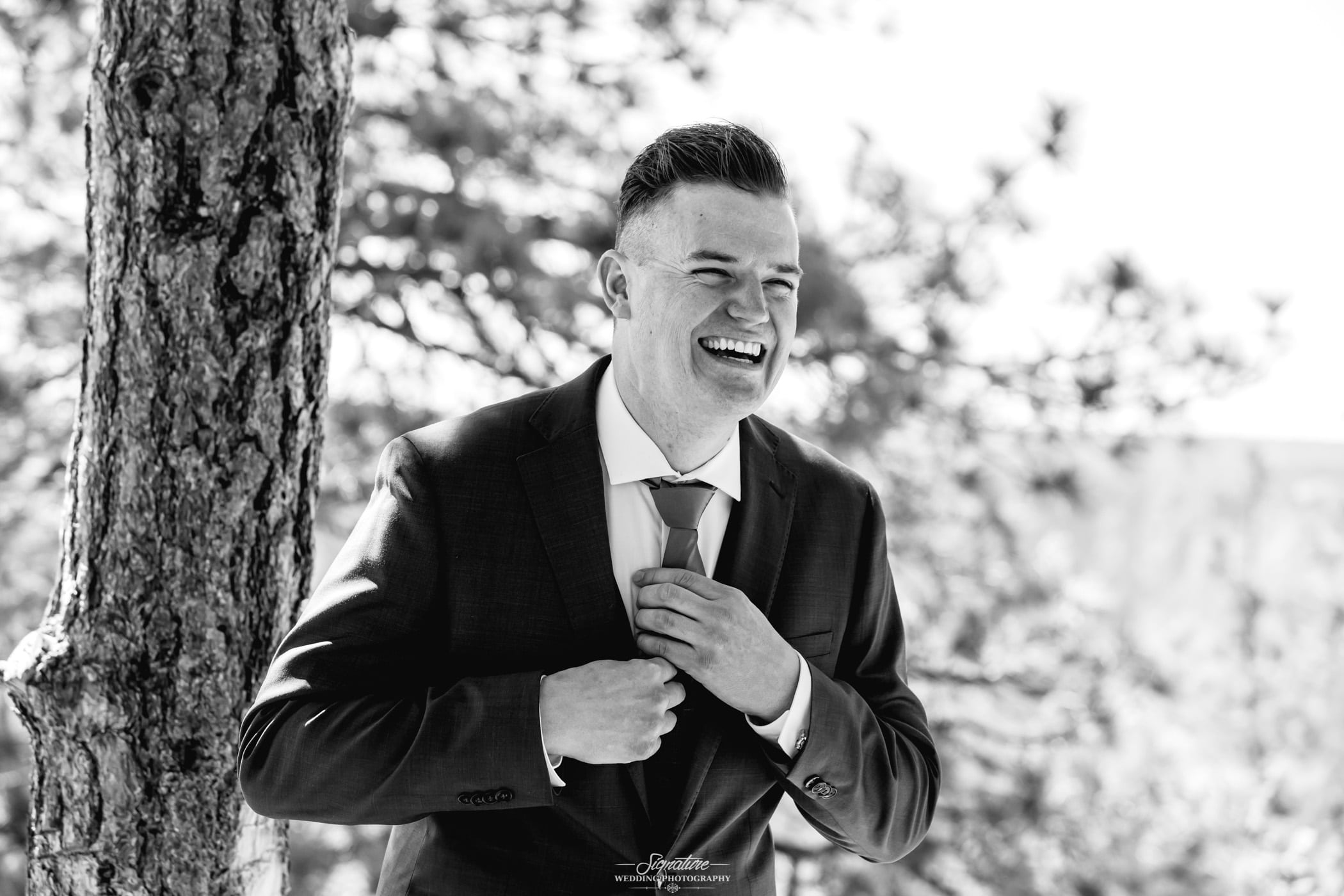 Groom smiling and fixing tie black and white
