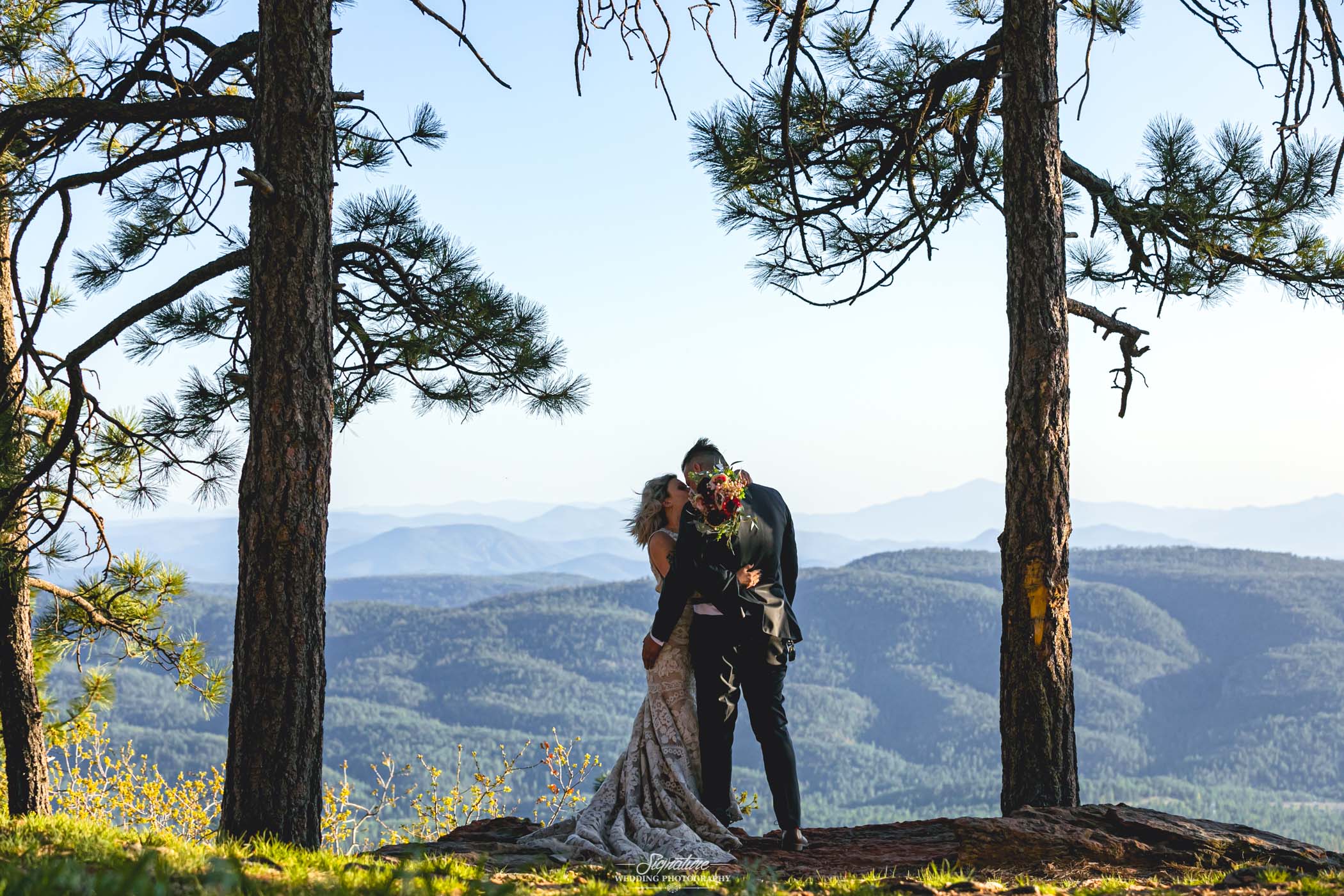 Bride and groom kissing on mountain top