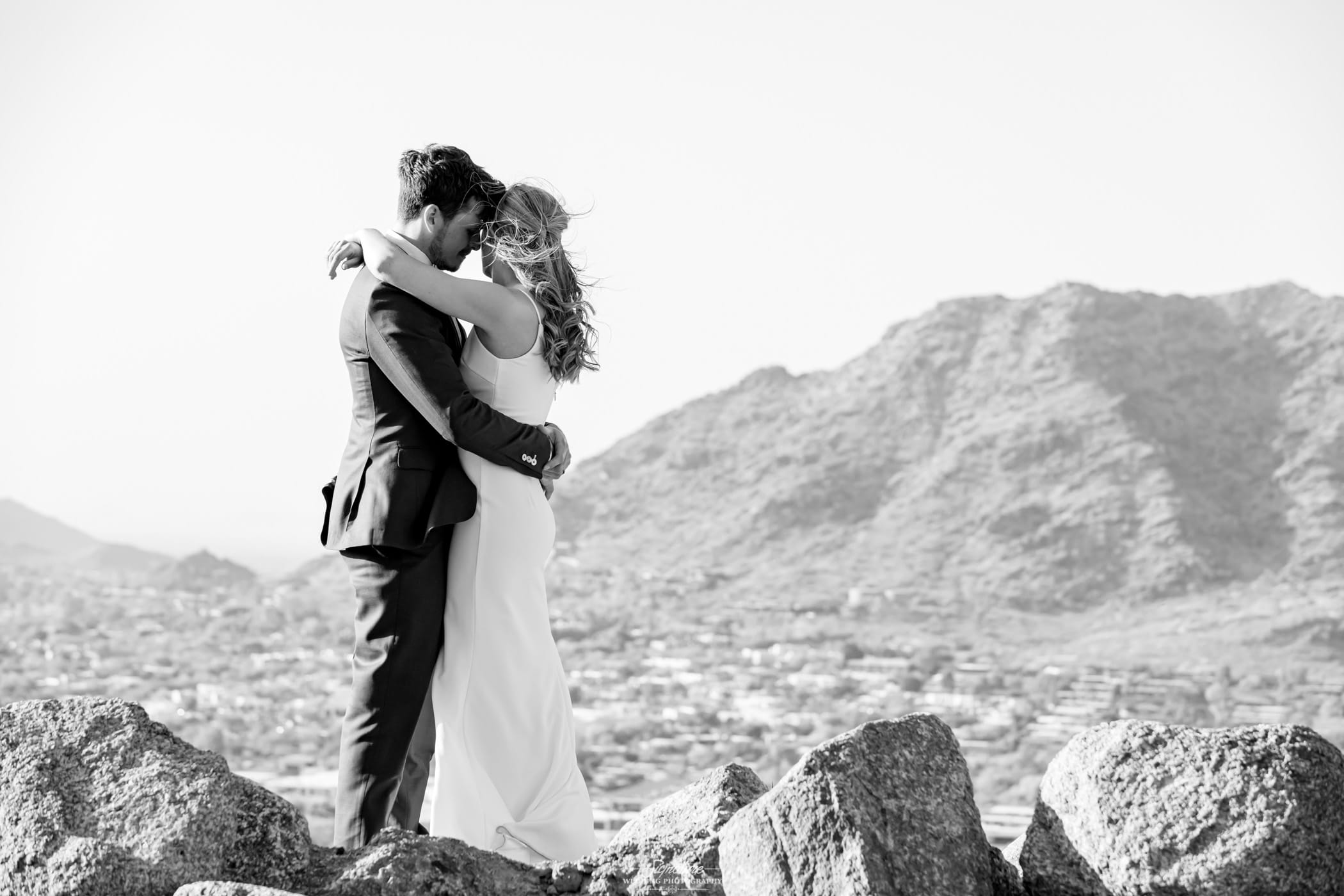 Bride and groom hugging on top of mountain black and white