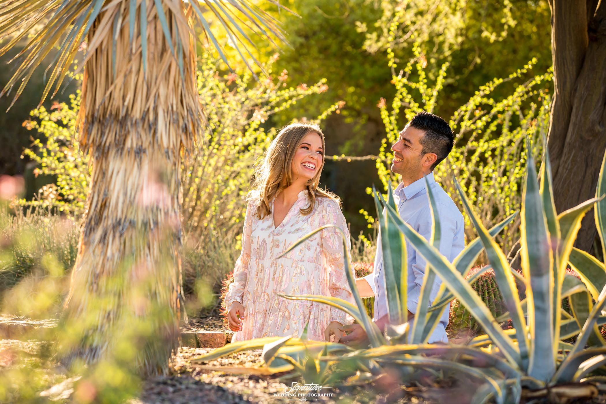 Couple looking over shoulder at each other smiling surrounded by desert plants