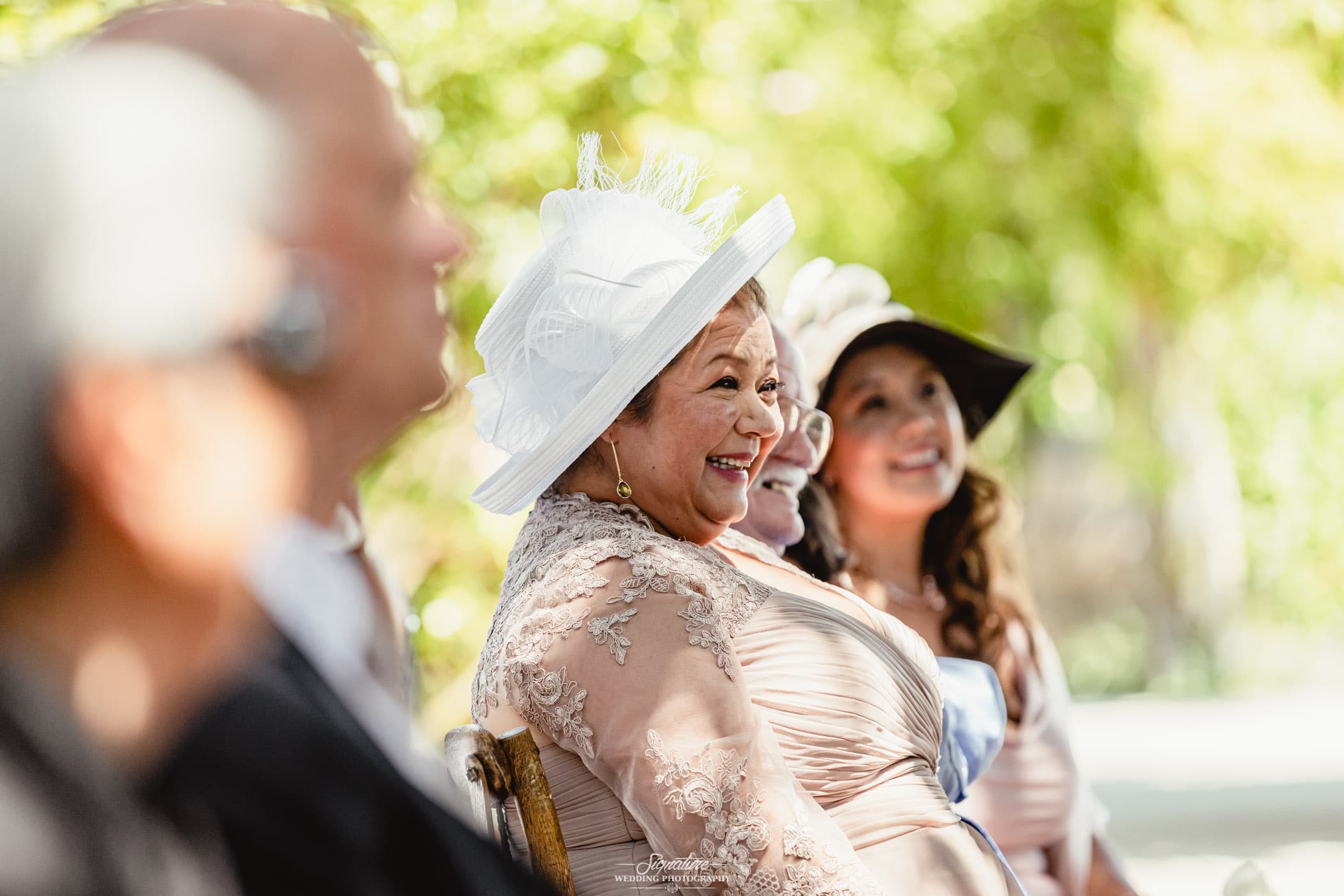 Woman in hat smiling during ceremony candid