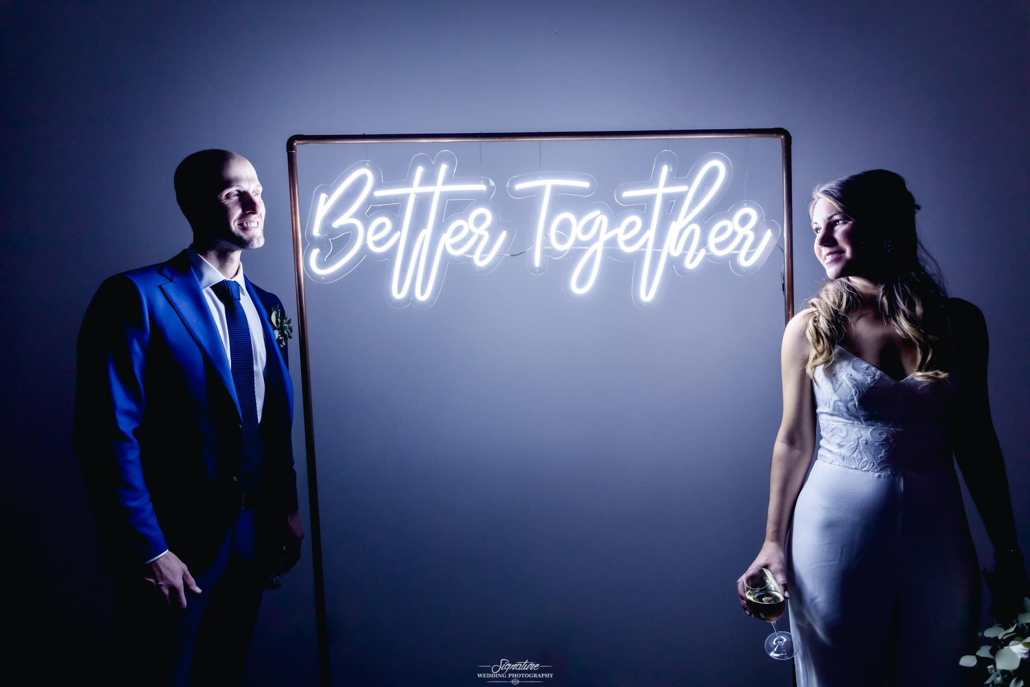 Bride and groom with neon better together sign