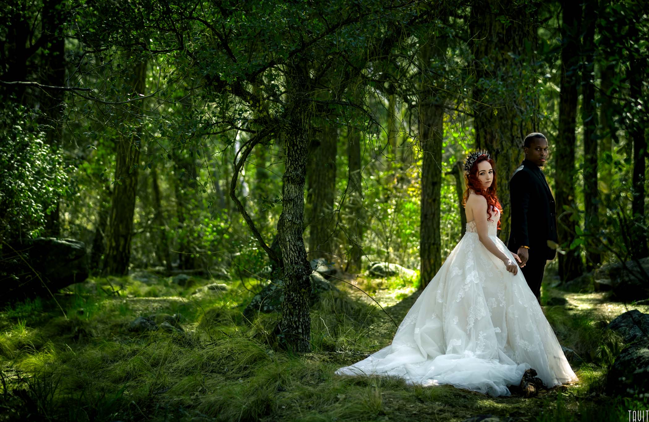 Bride and groom holding hands in green forest