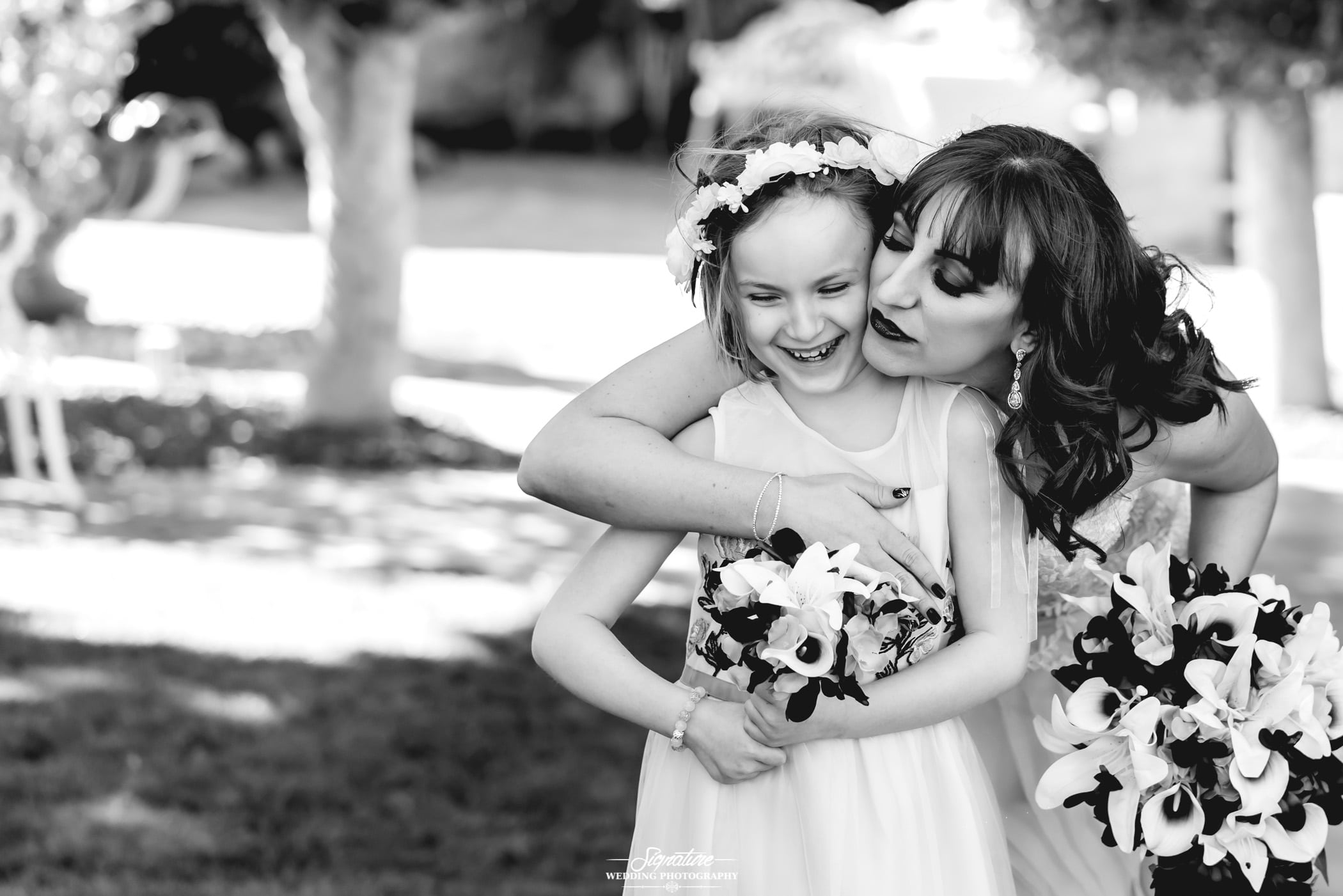Bride hugging daughter from behind black and white