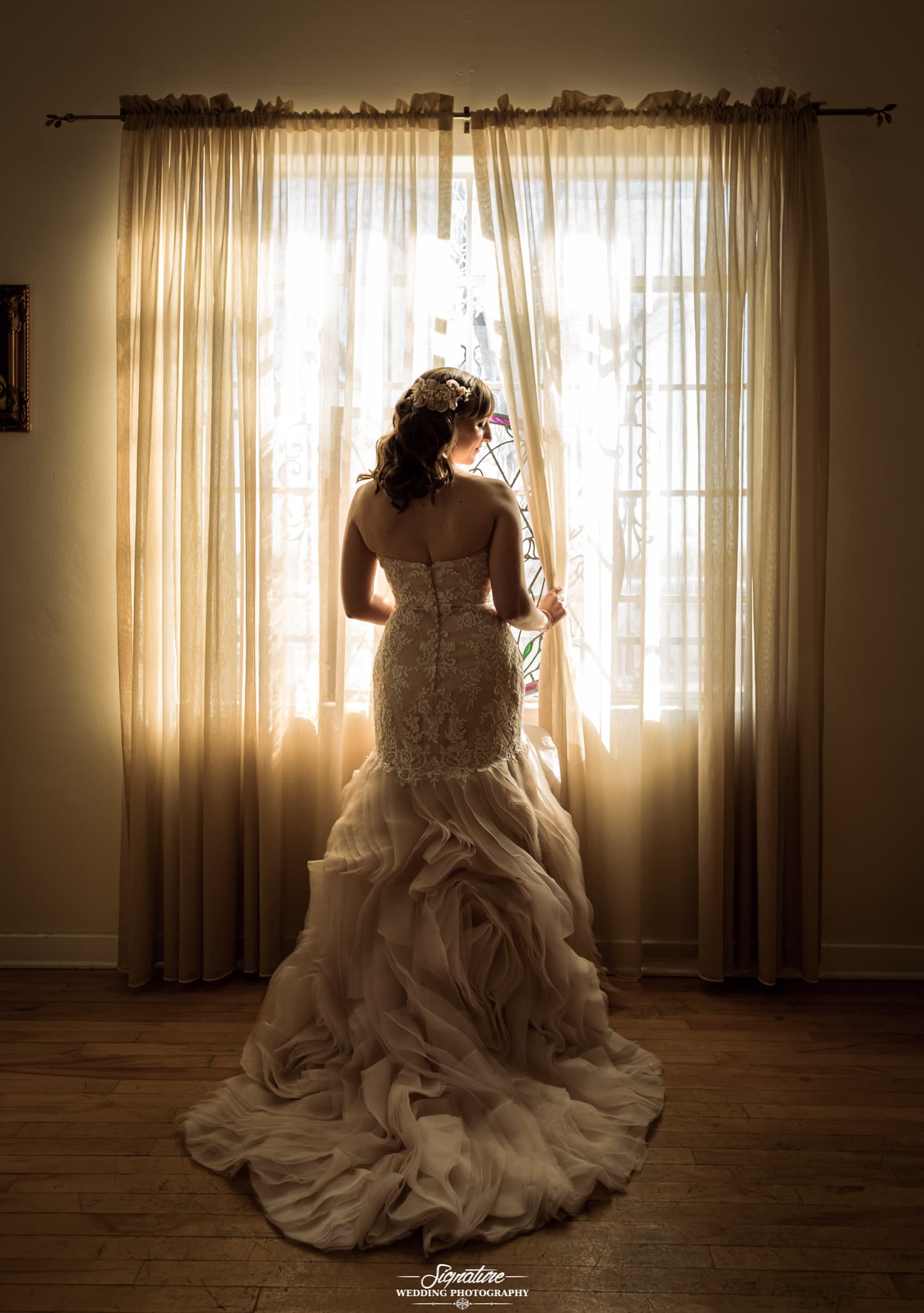 back of bride's dress in front of window looking over shoulder