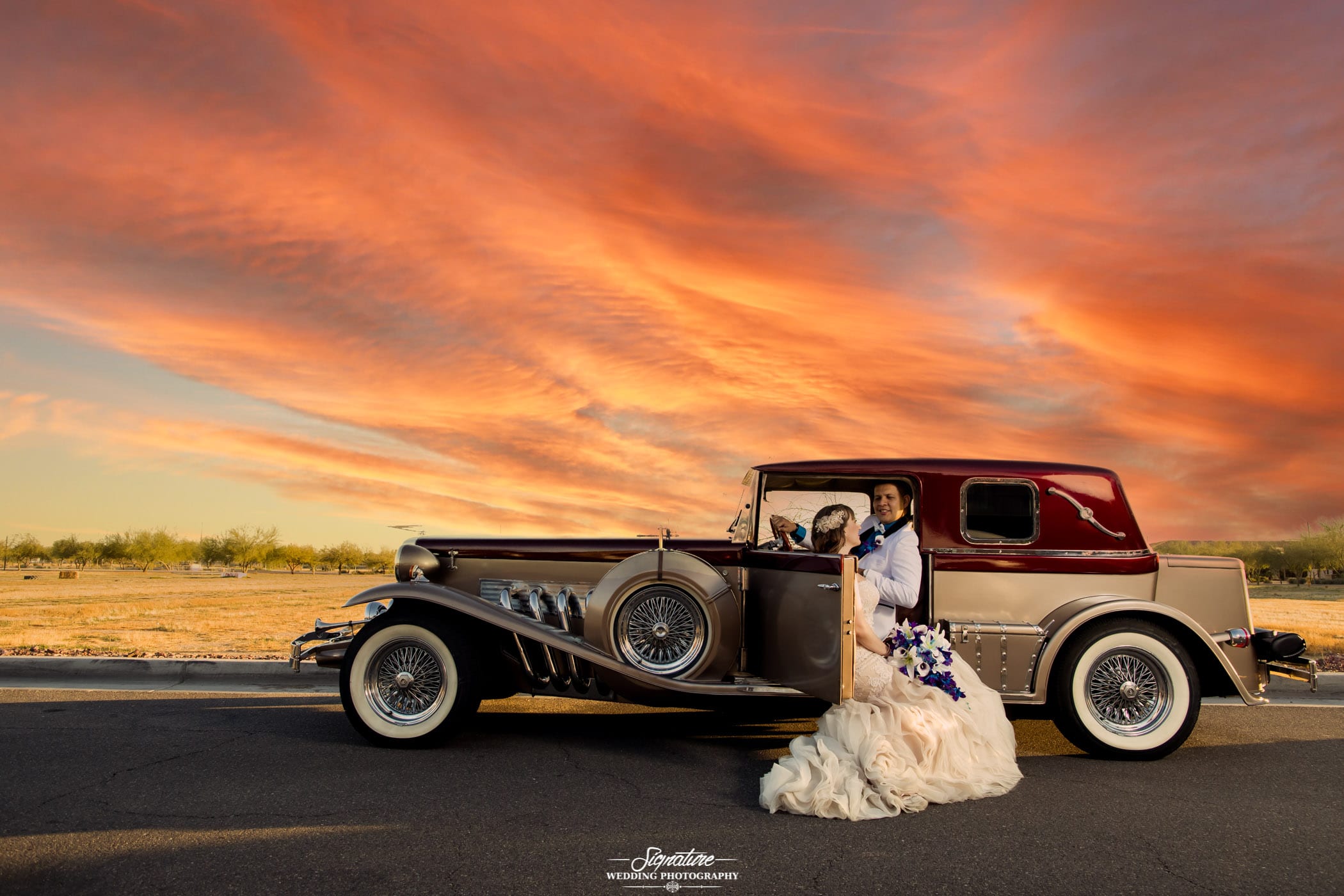 Bride and groom with vintage car at sunset