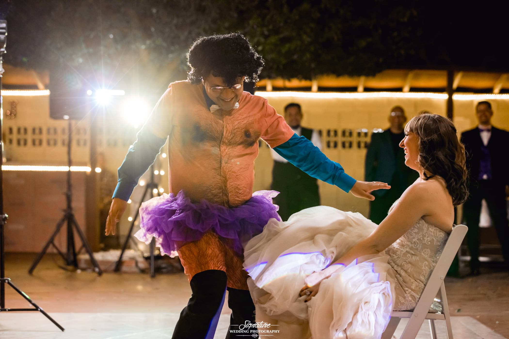 Man in tutu in front of bride for garter toss