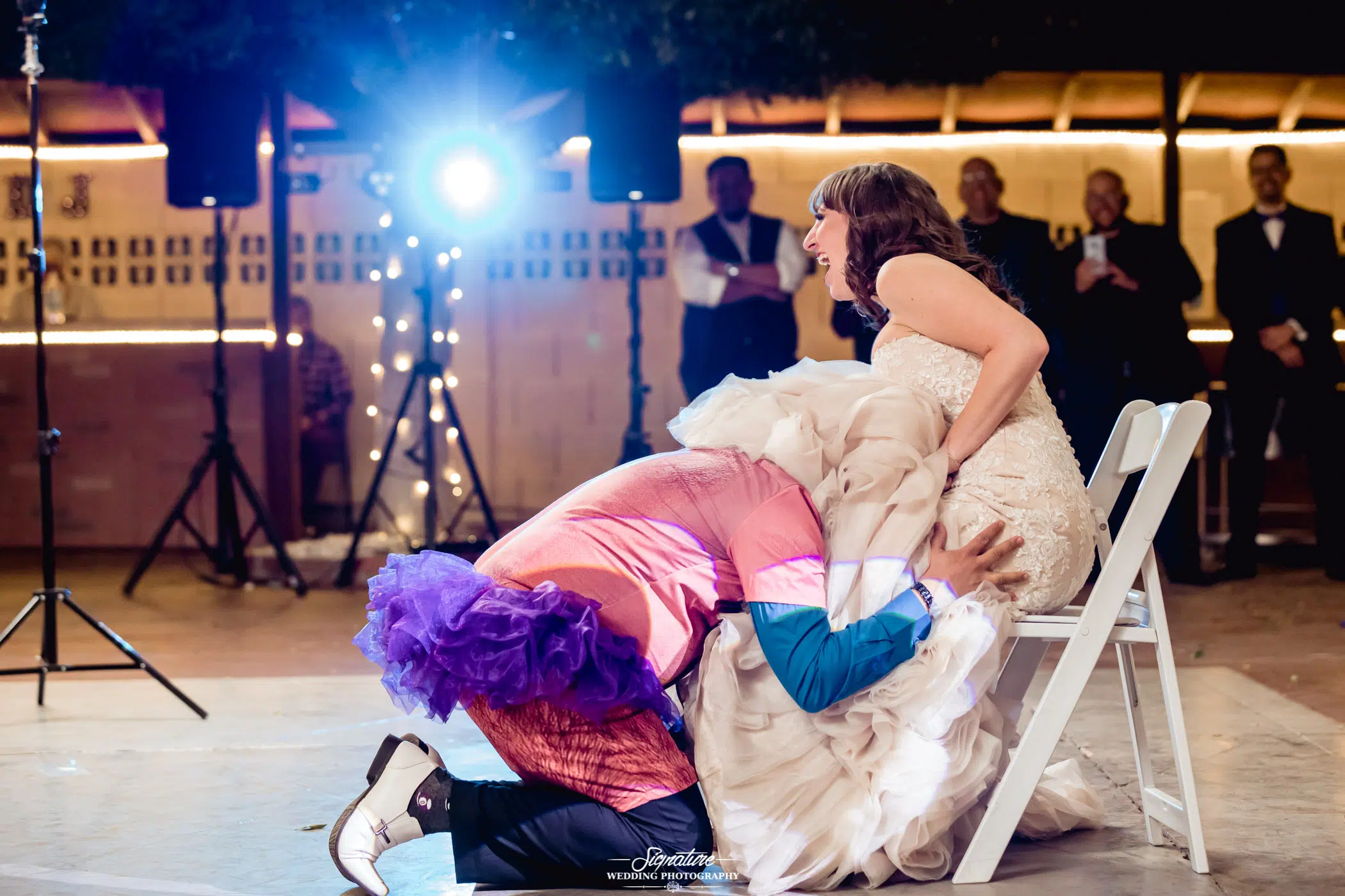 Person in tutu under brides dress for garter toss