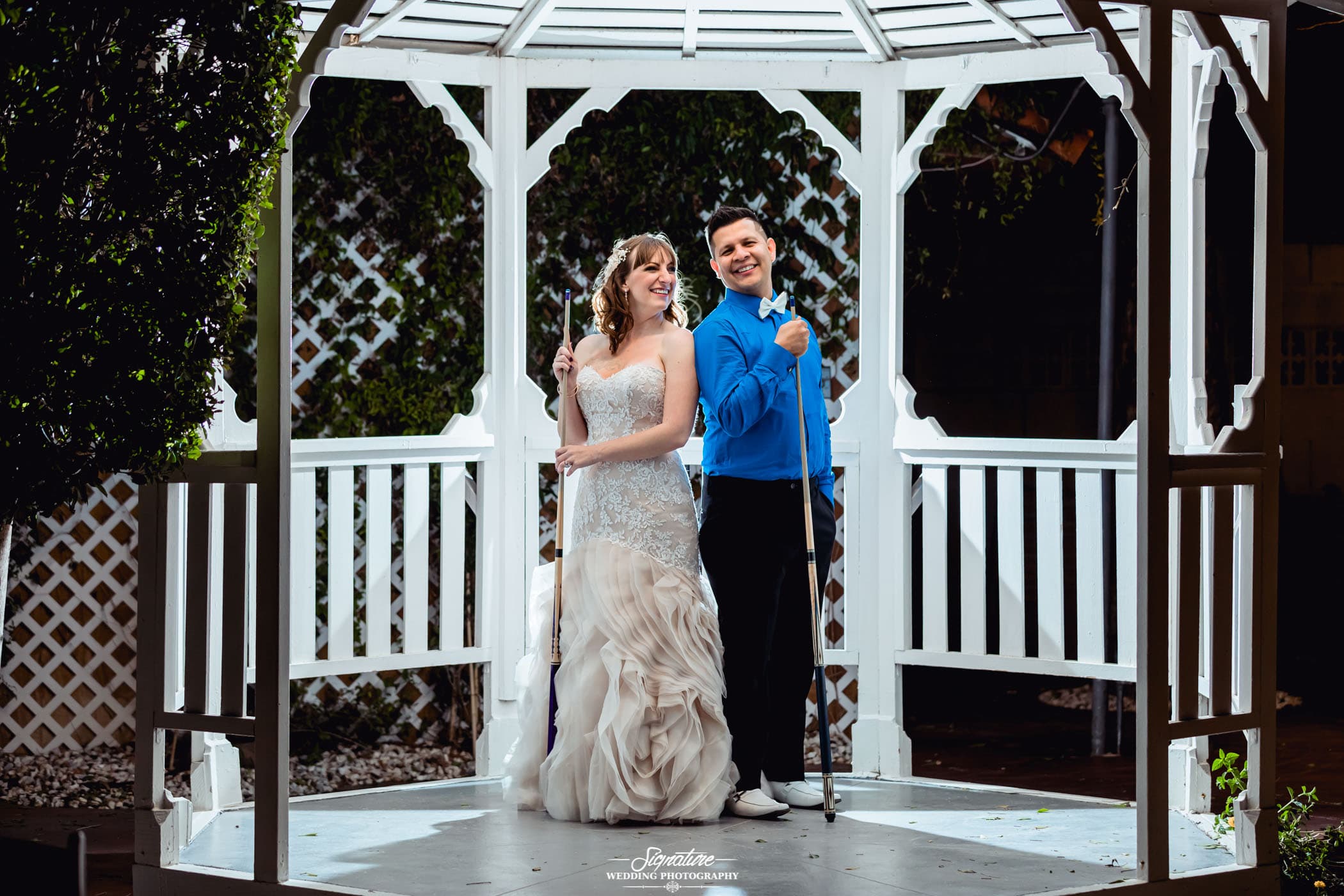 Bride and groom back to back under gazebo with pool sticks