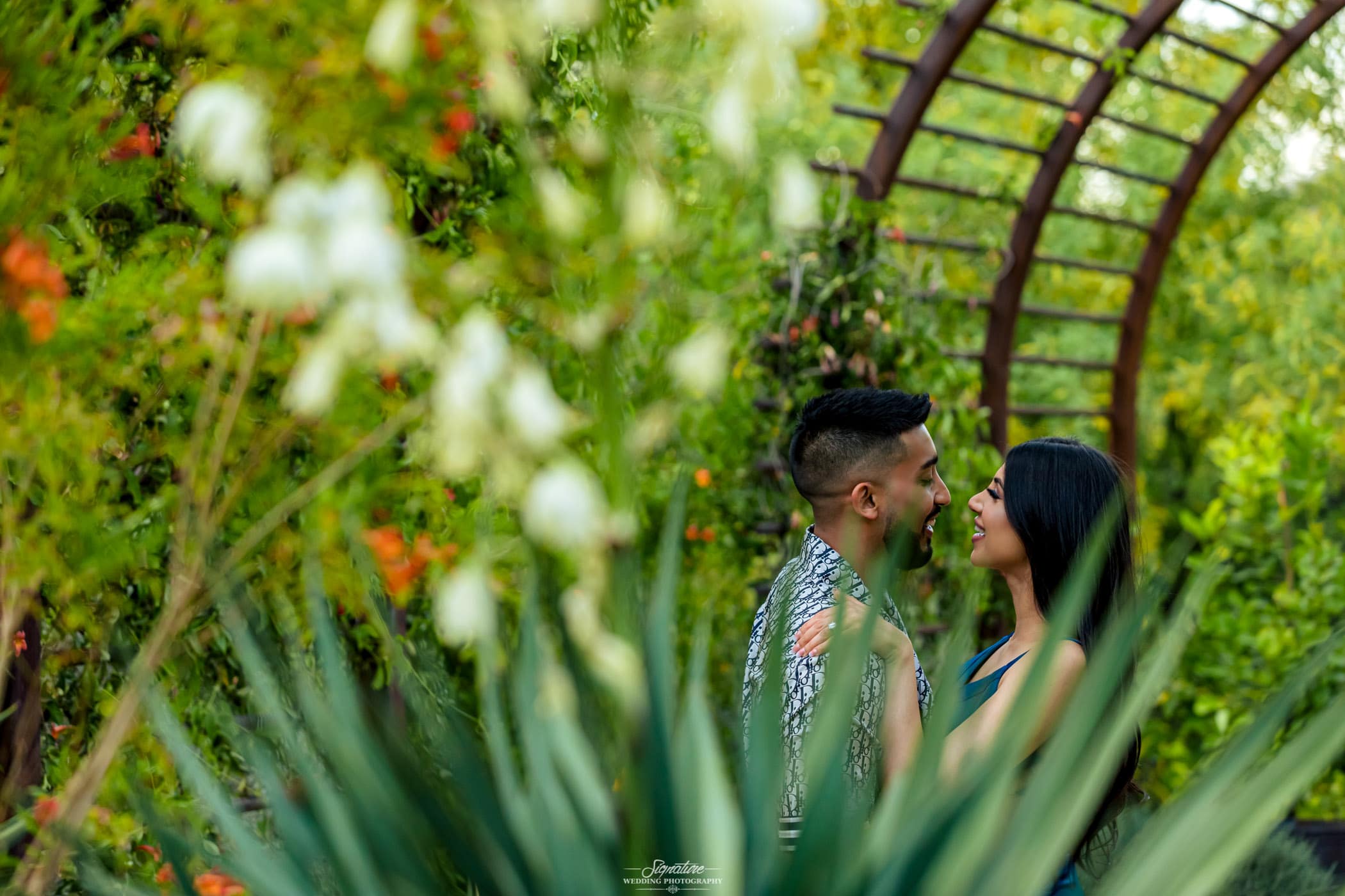 Couple smiling at each other behind desert plants