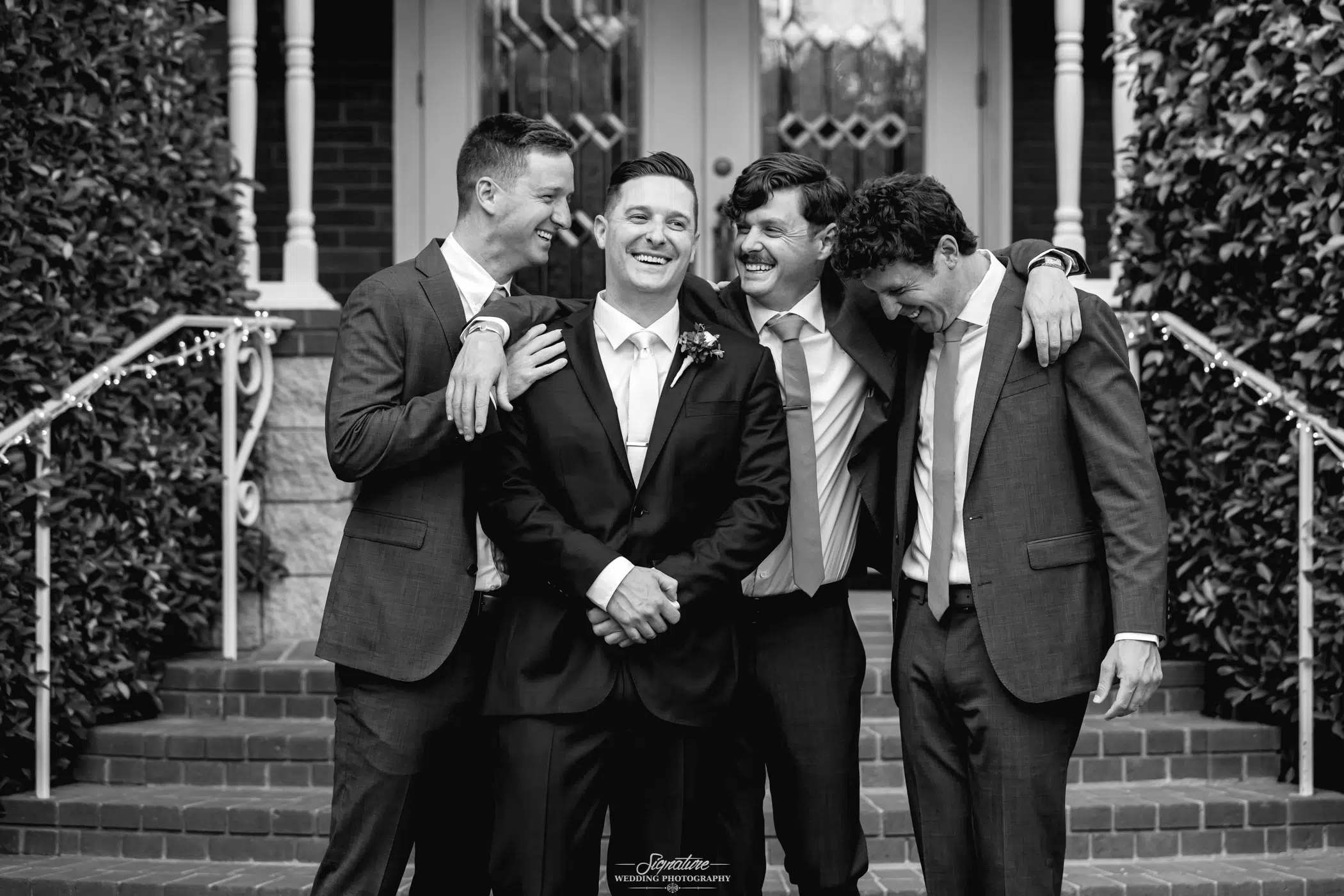 Groomsmen smiling around groom black and white