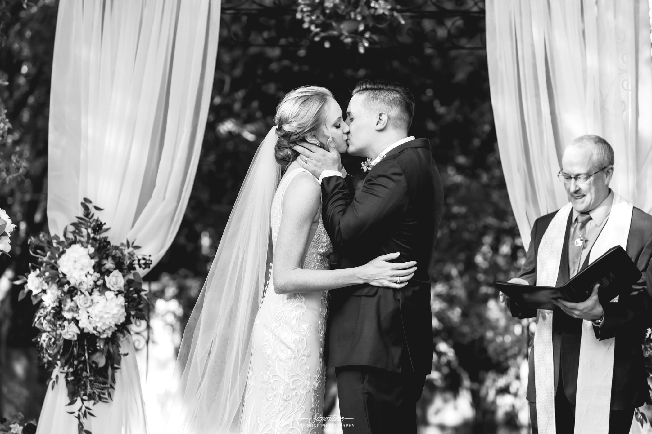 Bride and groom kissing after ceremony black and white