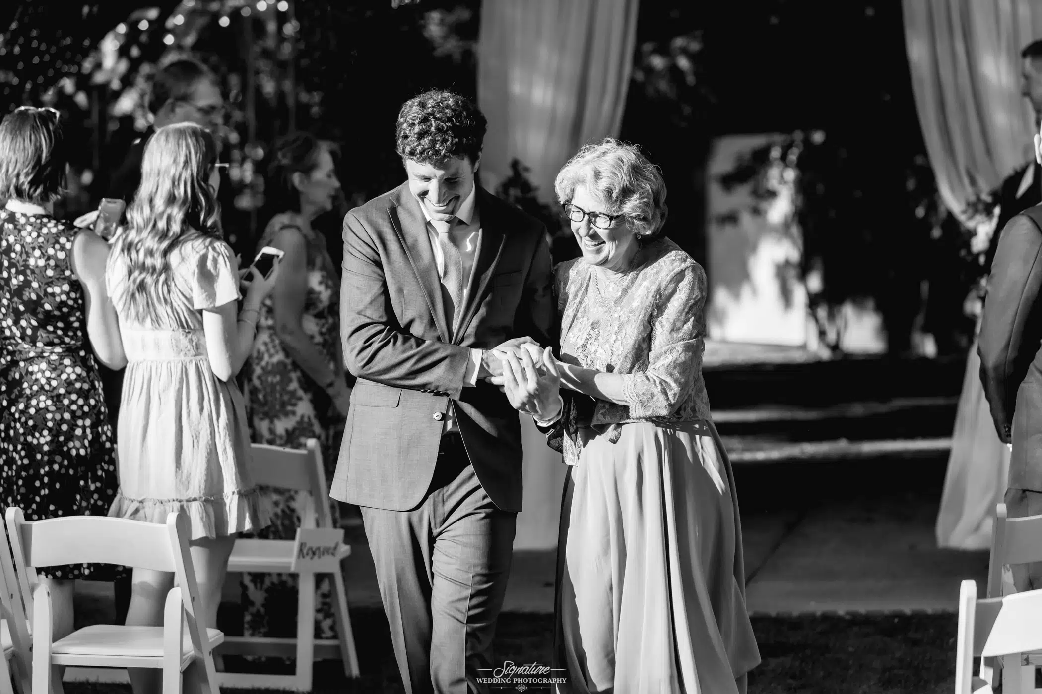 Man and matriarch of family walking down the isle black and white