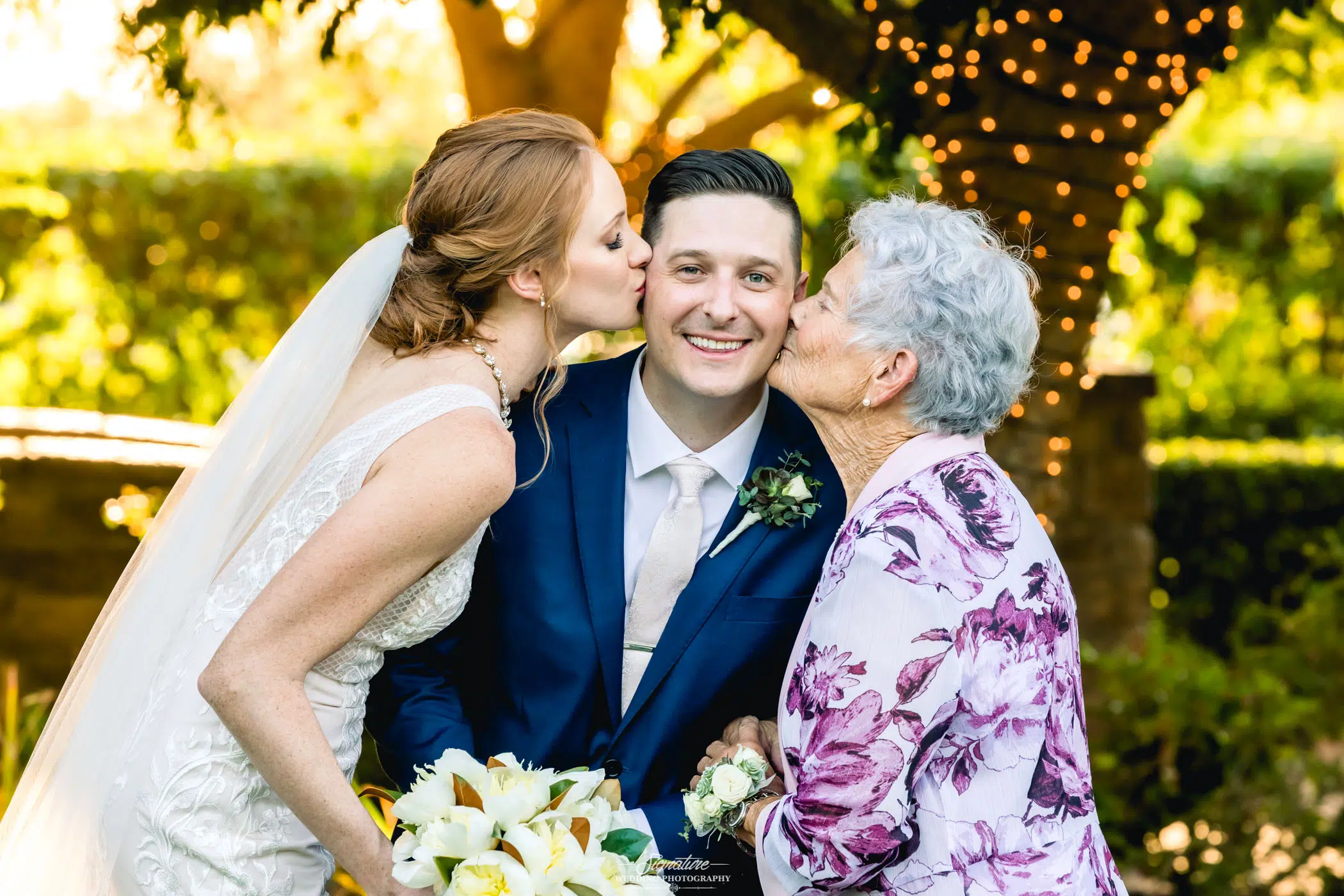 Bride and matriarch of family kiss groom on cheeks