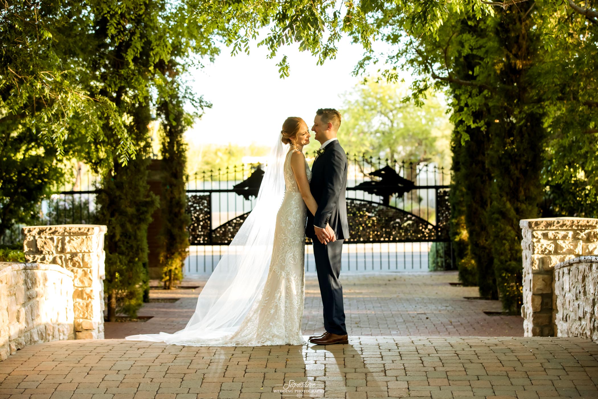 Bride and groom holding hands in front of gate