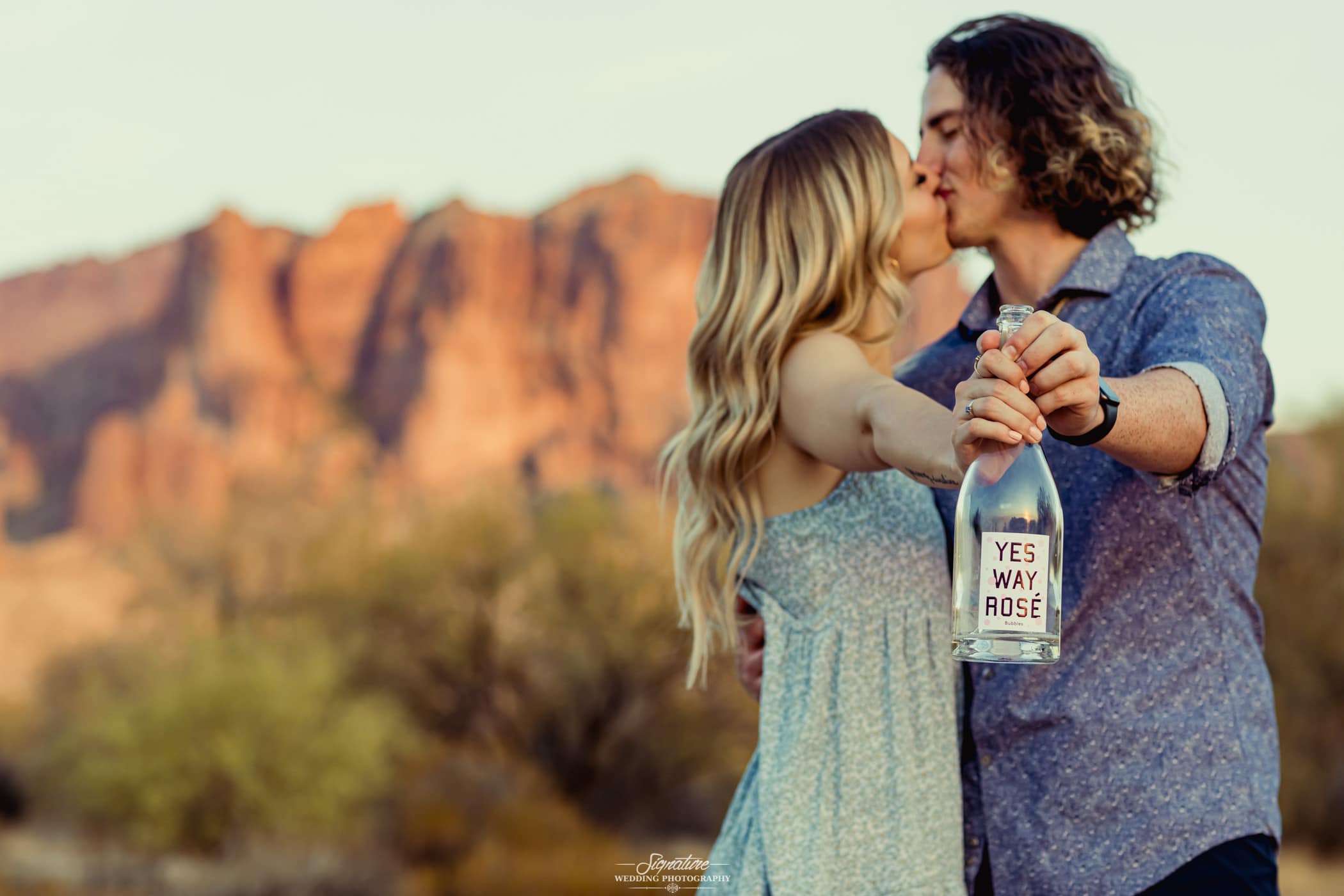 Couple kissing holding engagement bottle