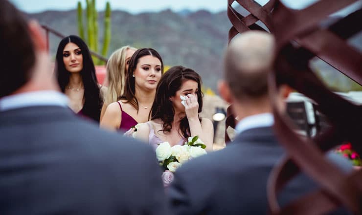 Maid of honor wiping tears during ceremony