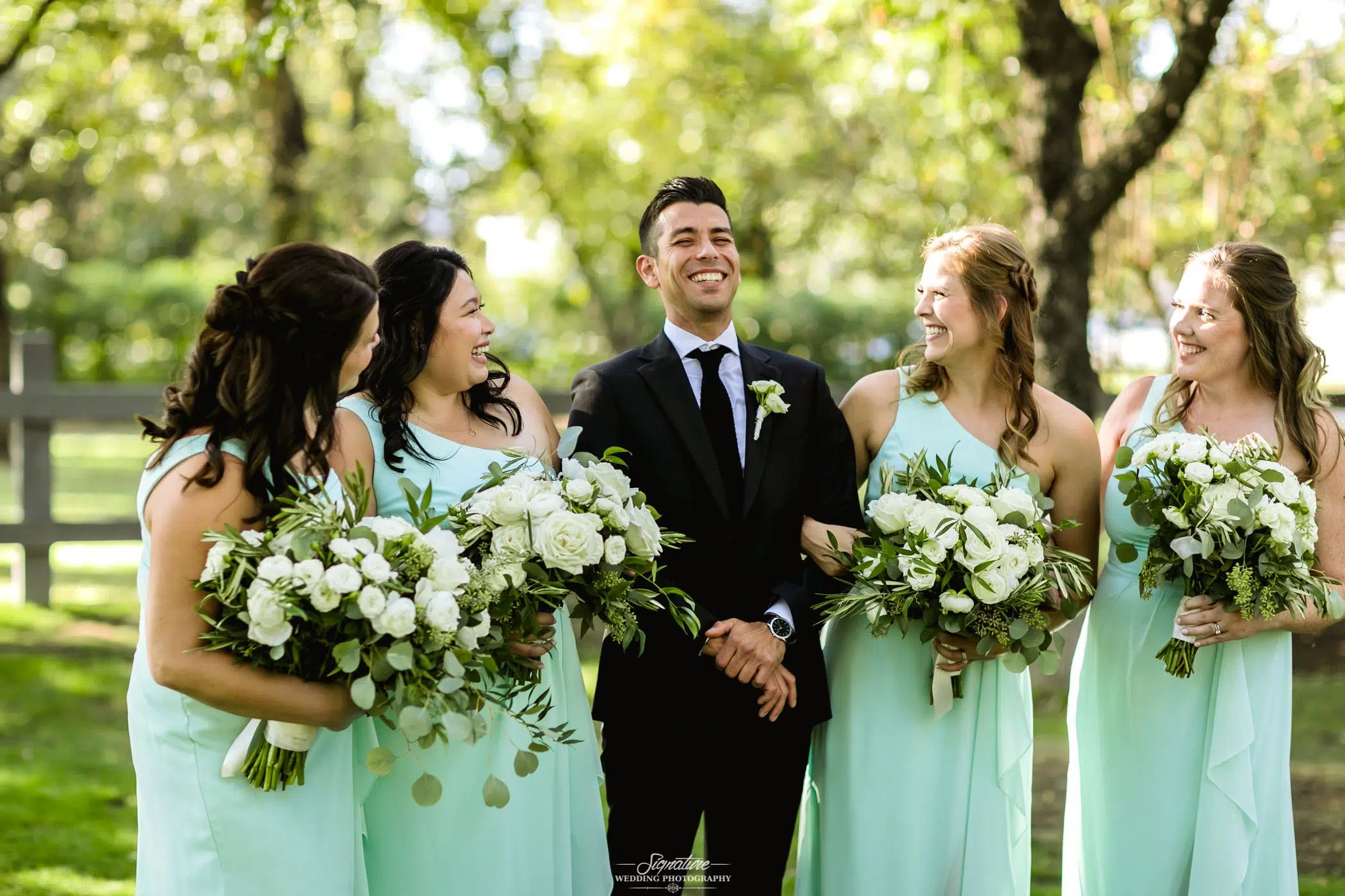 Groom with bridesmaids smiling