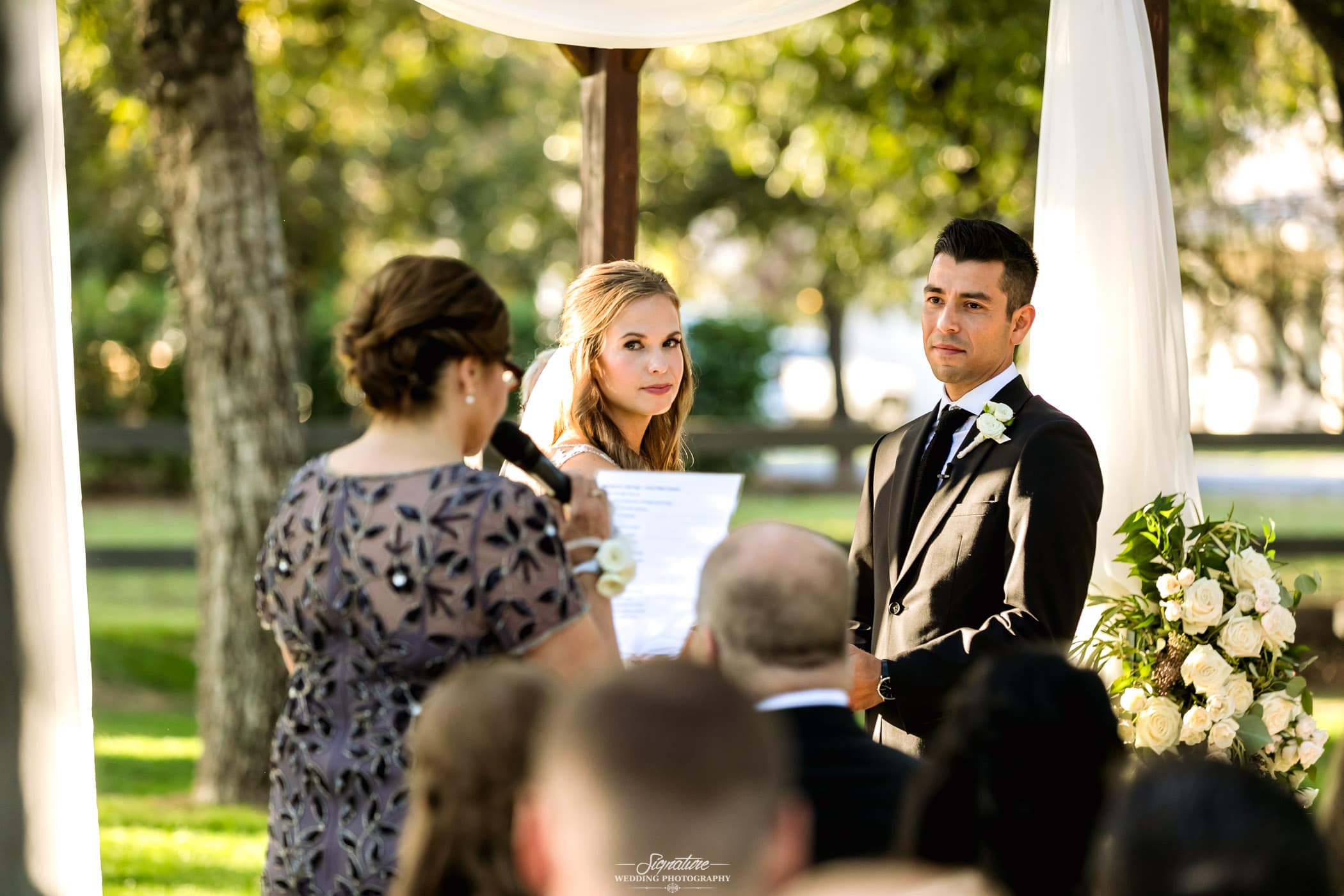 Bride and groom looking at speaker with mic
