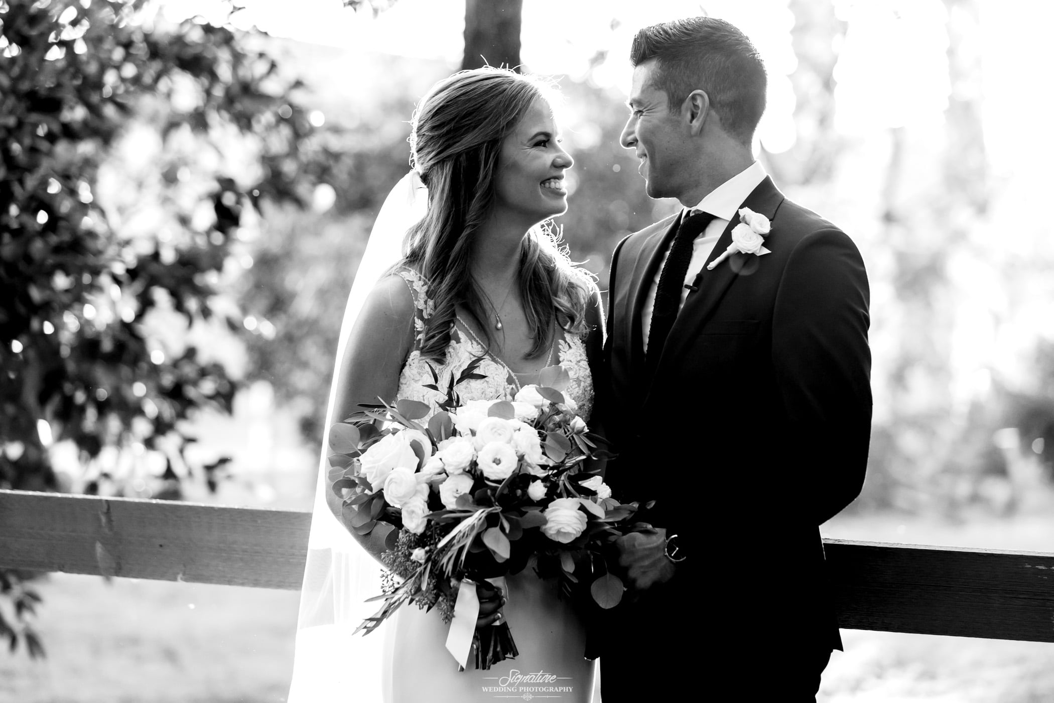 Bride and groom smiling at each other black and white