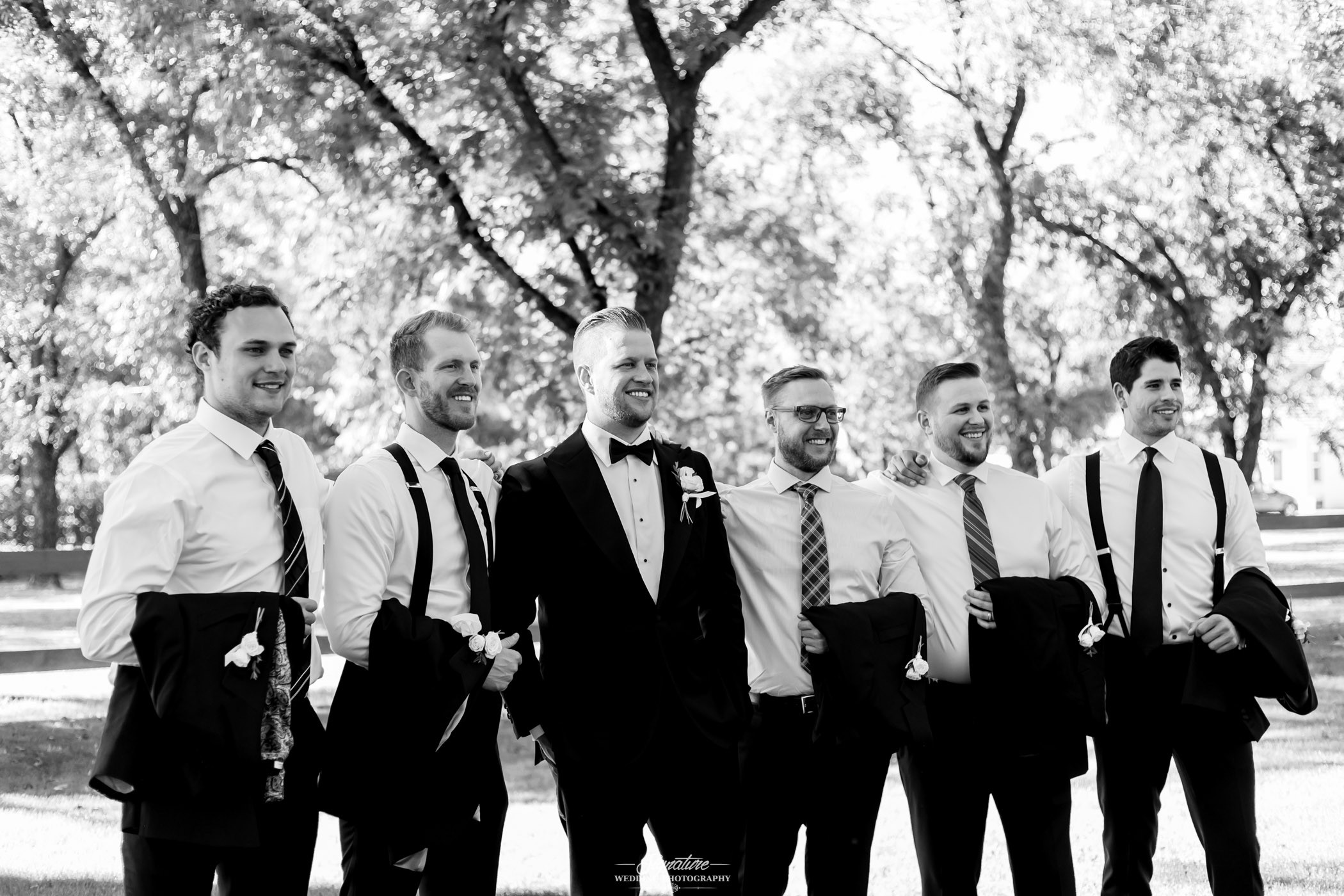 Groom and groomsmen smiling black and white