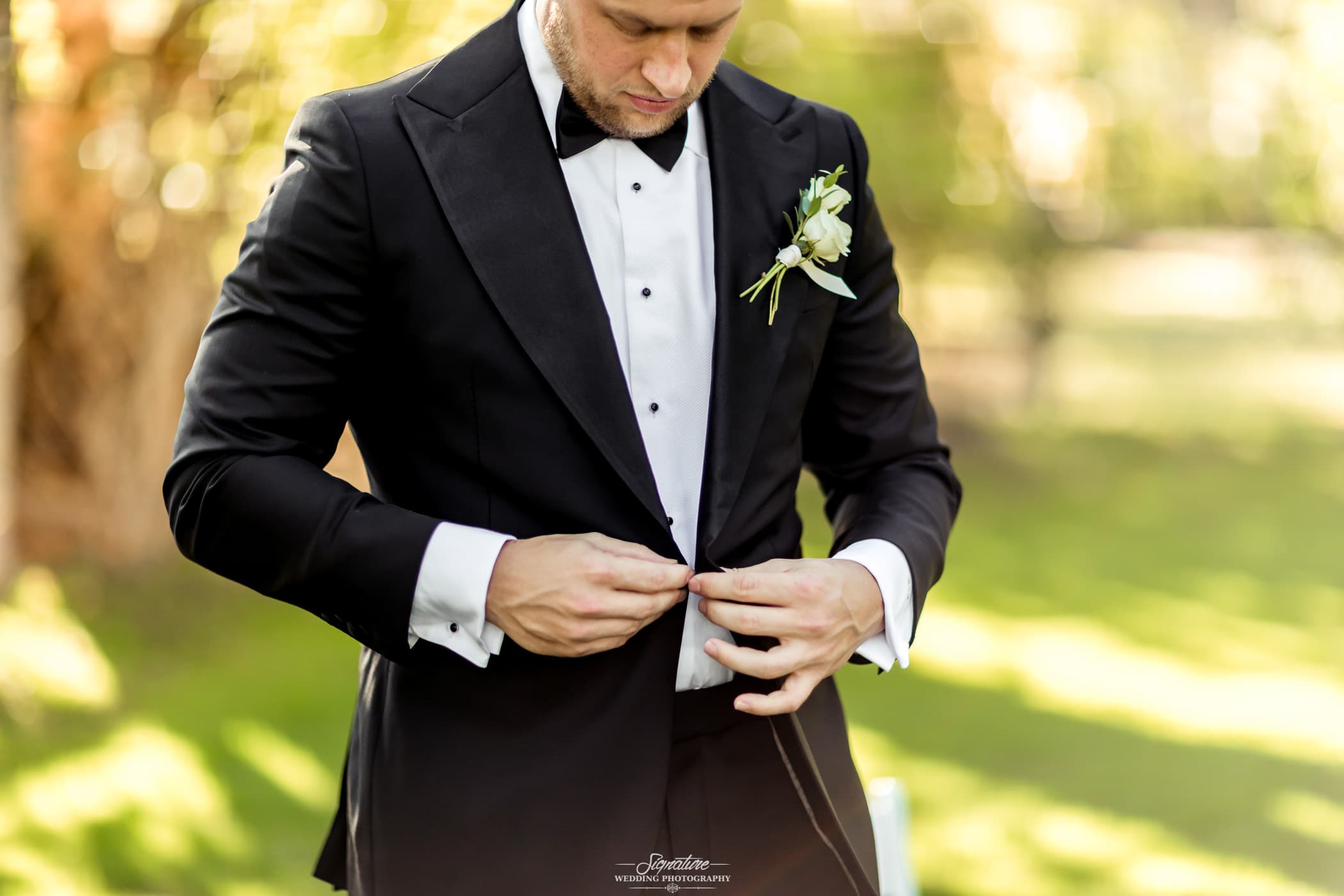 Groom looking down fastening suit button