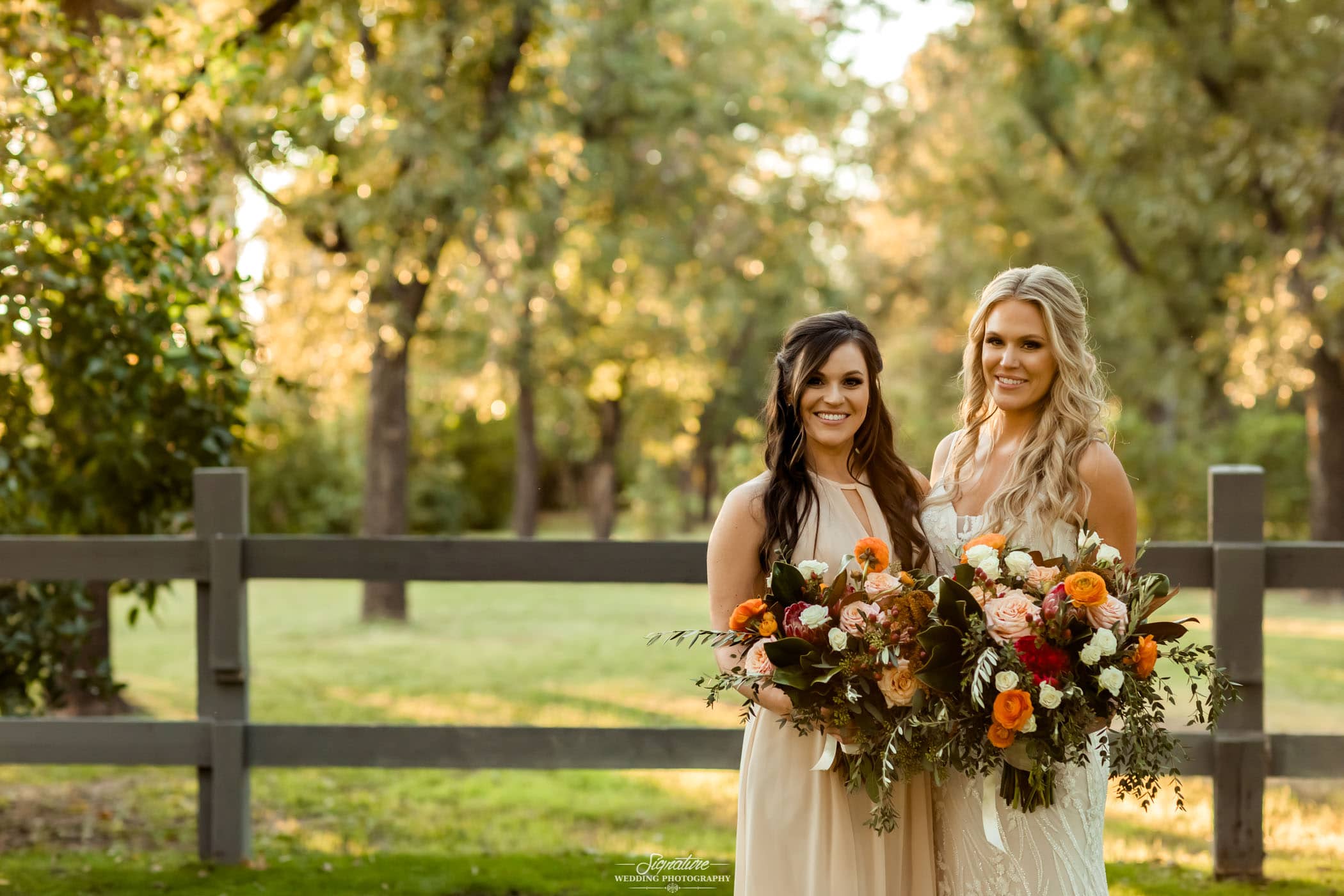 Bride and maid of honor smiling at camera outside