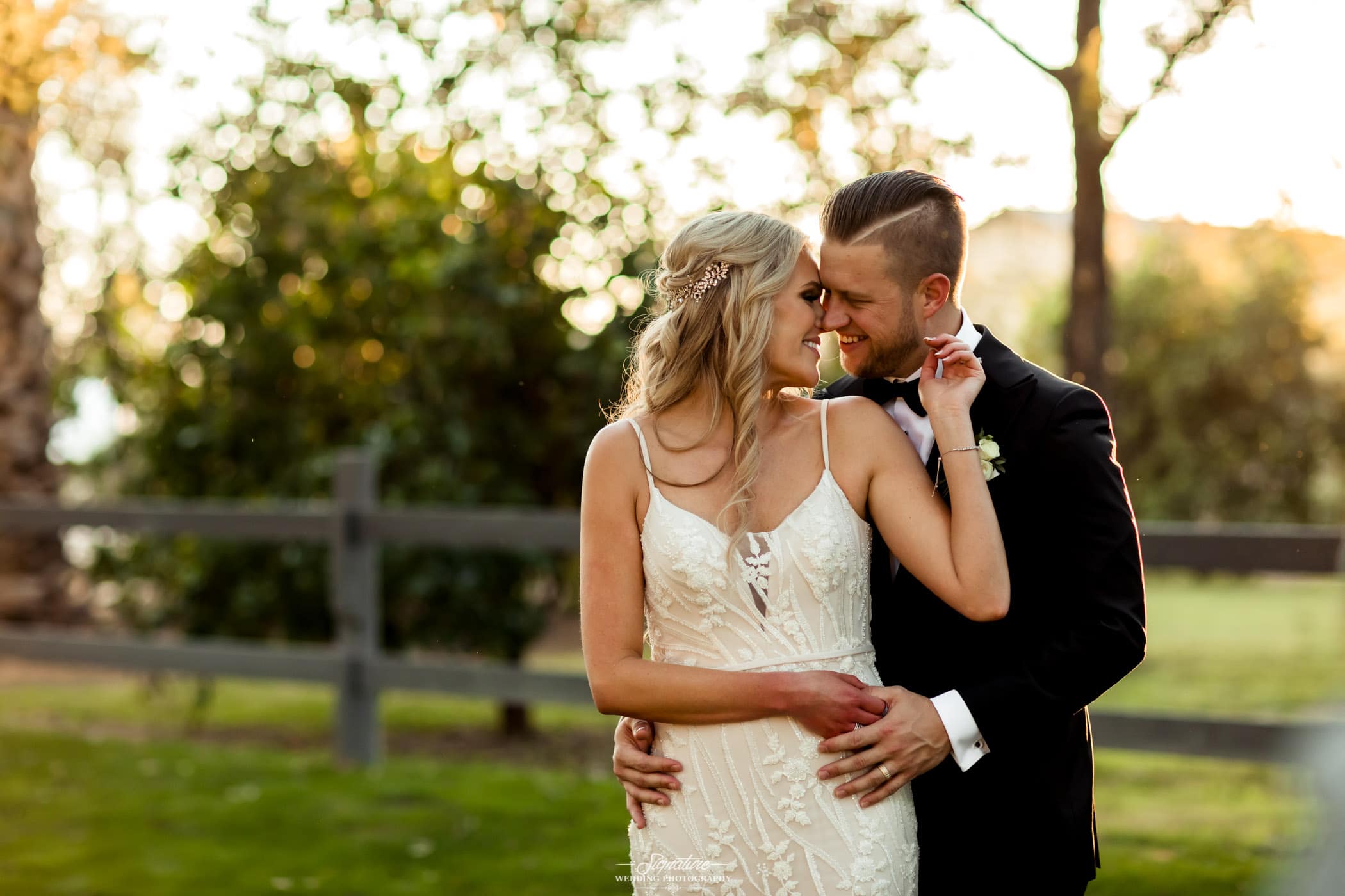 Groom holding brides waist nose to nose outside