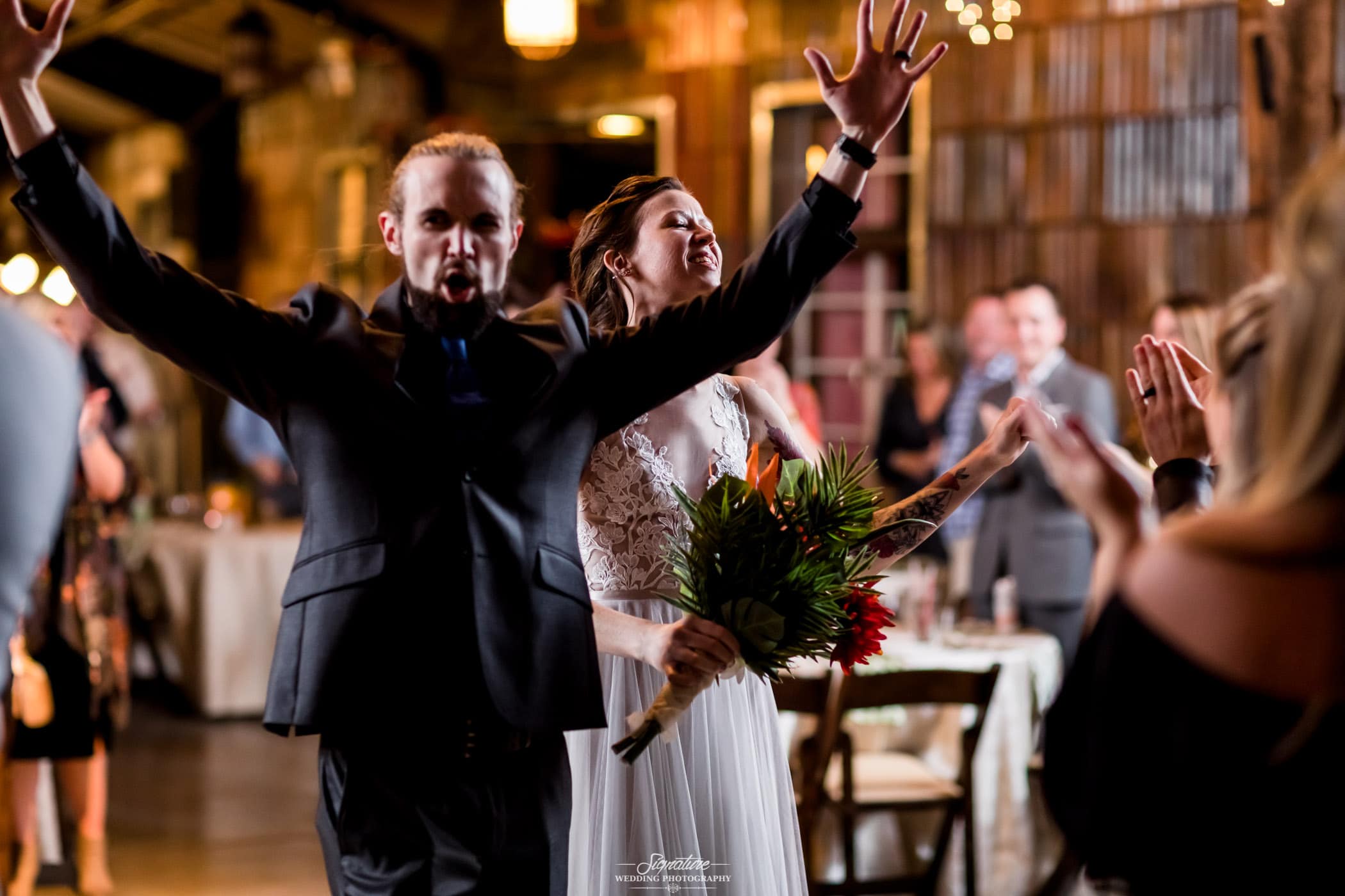 Groom with arms up and bride holding bouquet