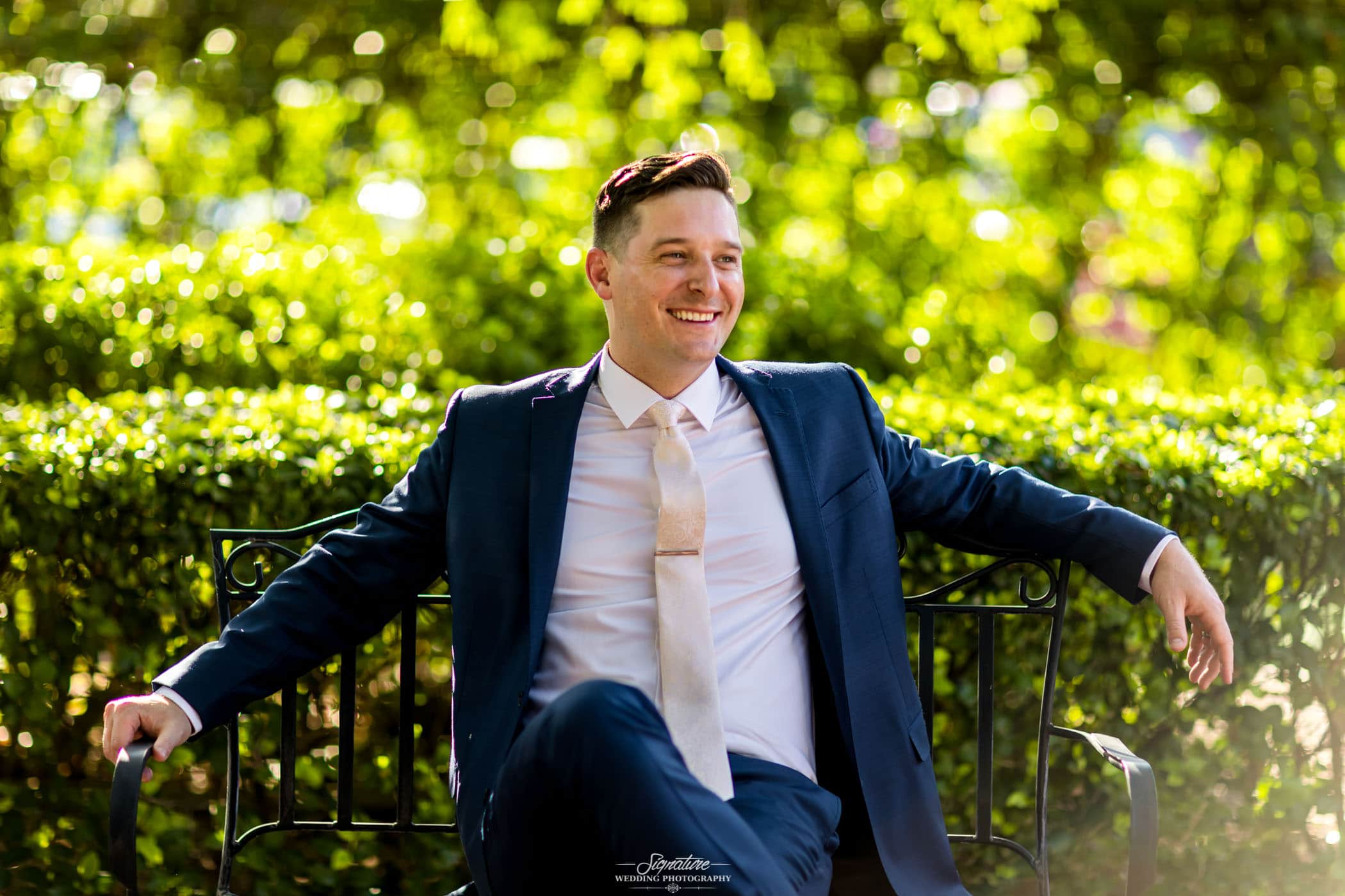 Groom sitting on bench smiling