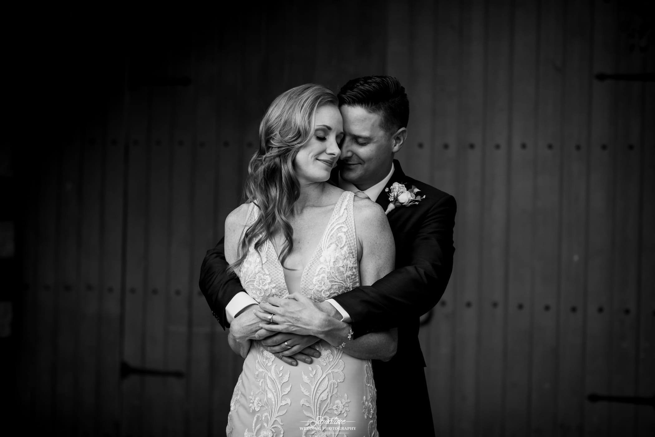 Groom with arms around bride eyes closed black and white