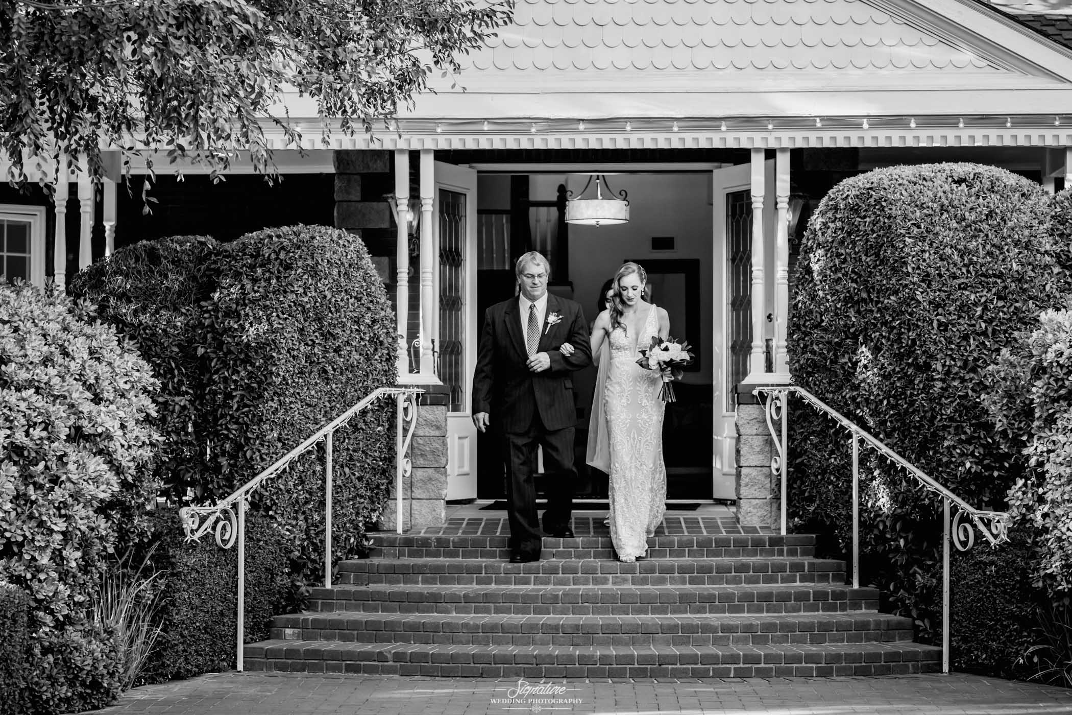 Father walking bride down stairs black and white