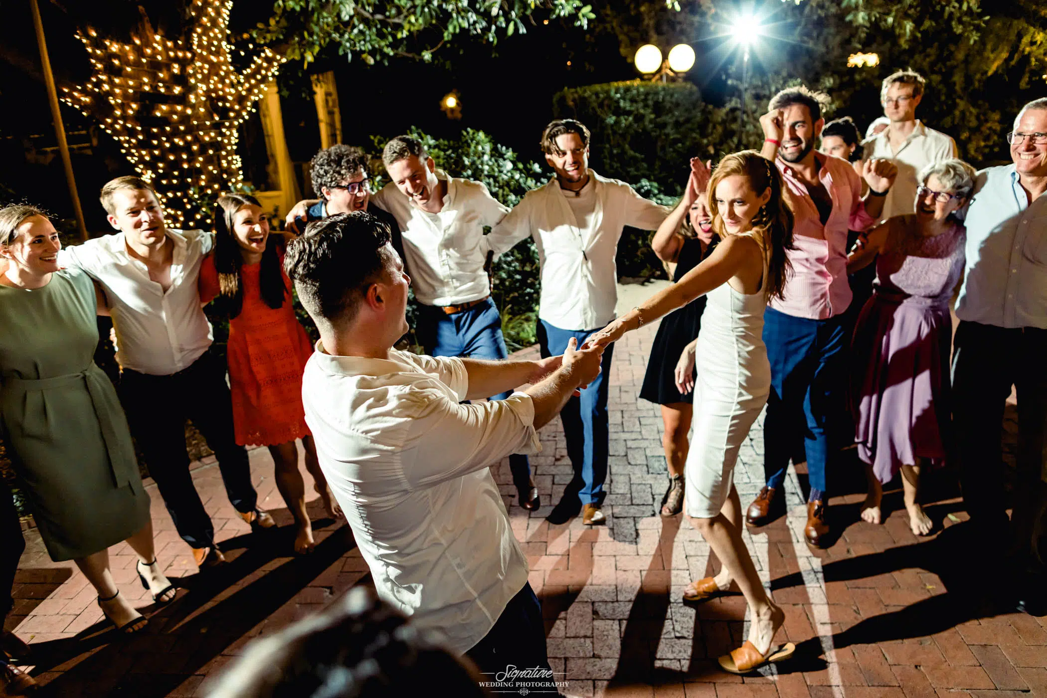 Bride and groom dancing surrounded by wedding guests