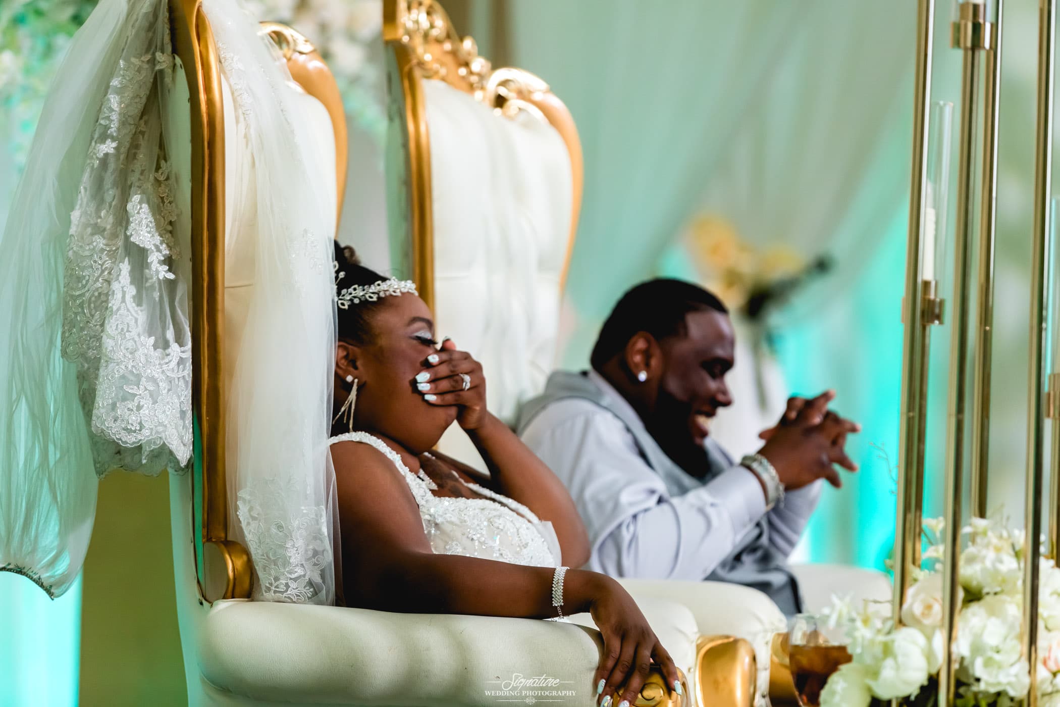 Bride covering mouth and groom laughing at sweetheart table