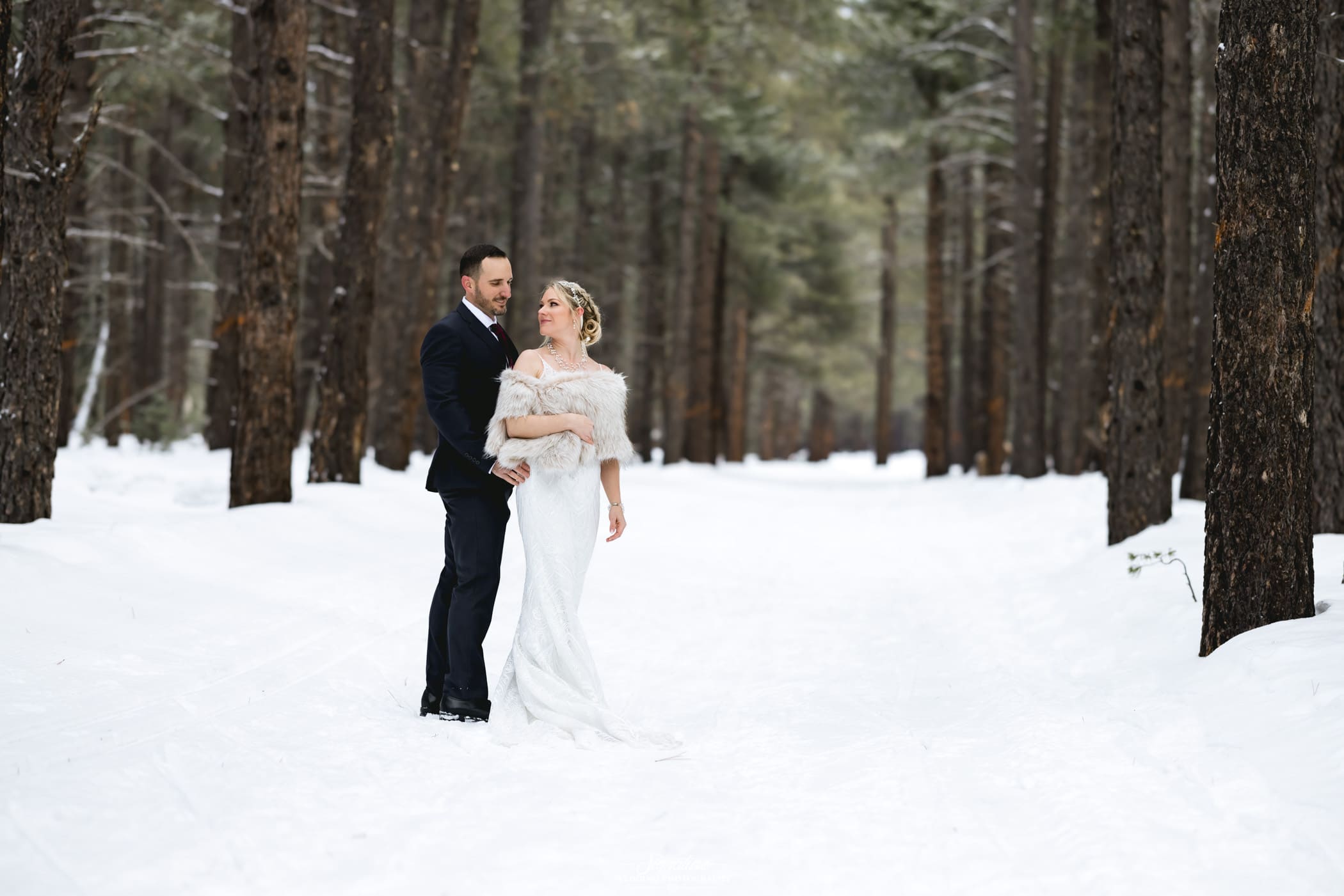 Bride and groom looking at each other in forest with snow