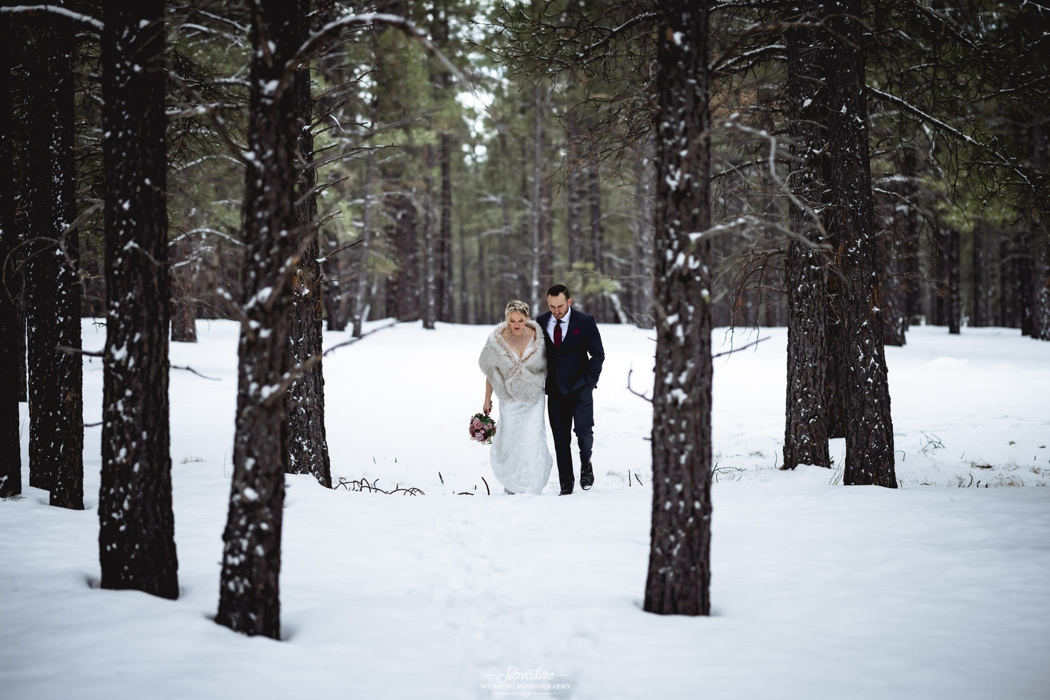 Bride and groom walking in winter forest