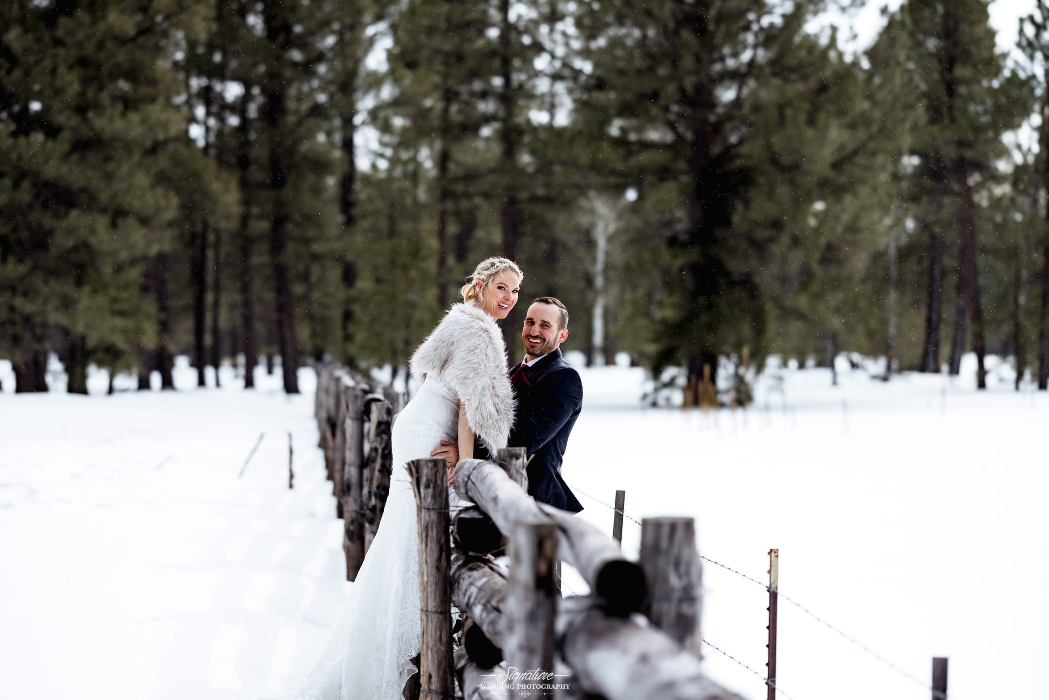 Bride and groom smiling on wooden fence