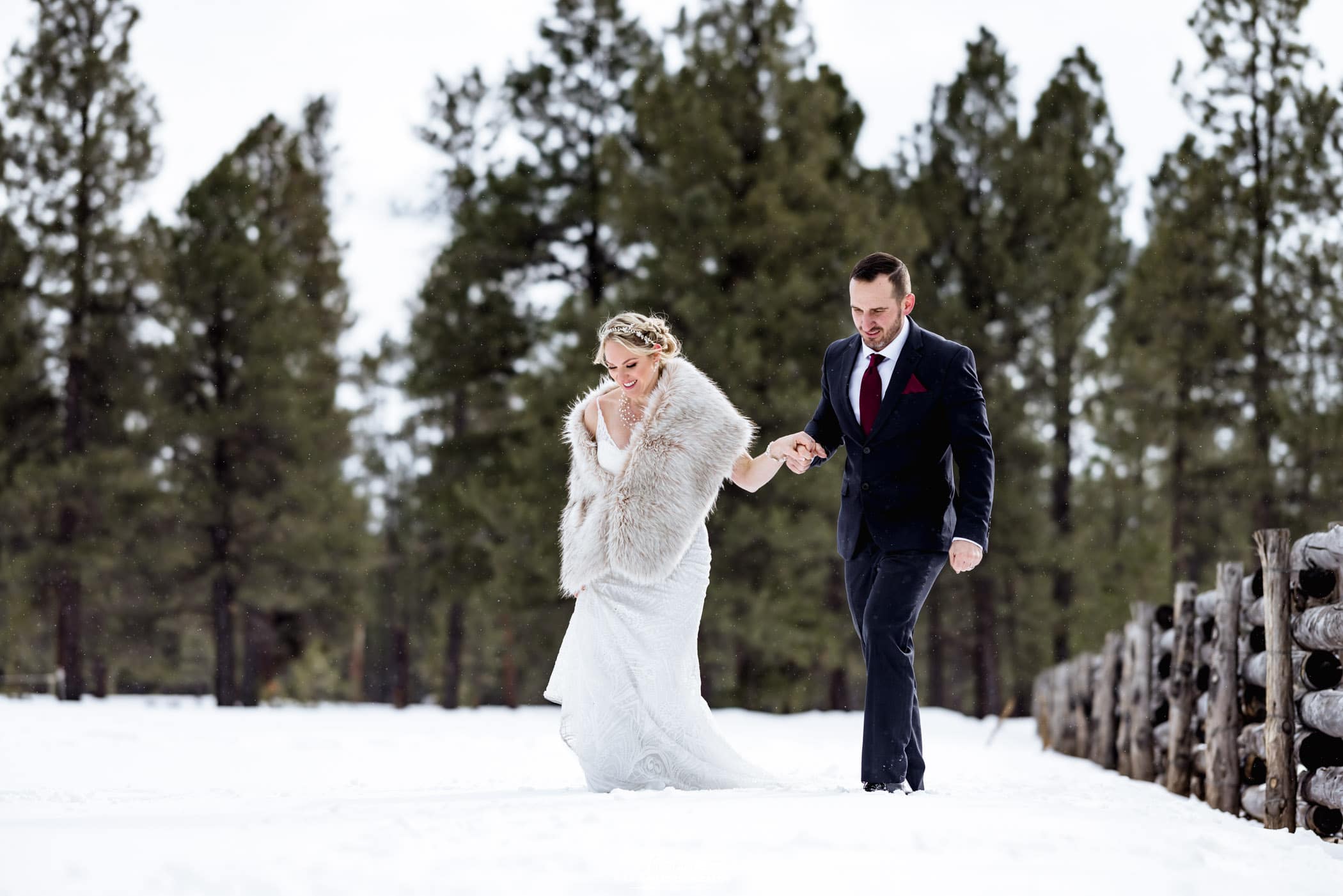 Bride and groom holding hands smiling in snow