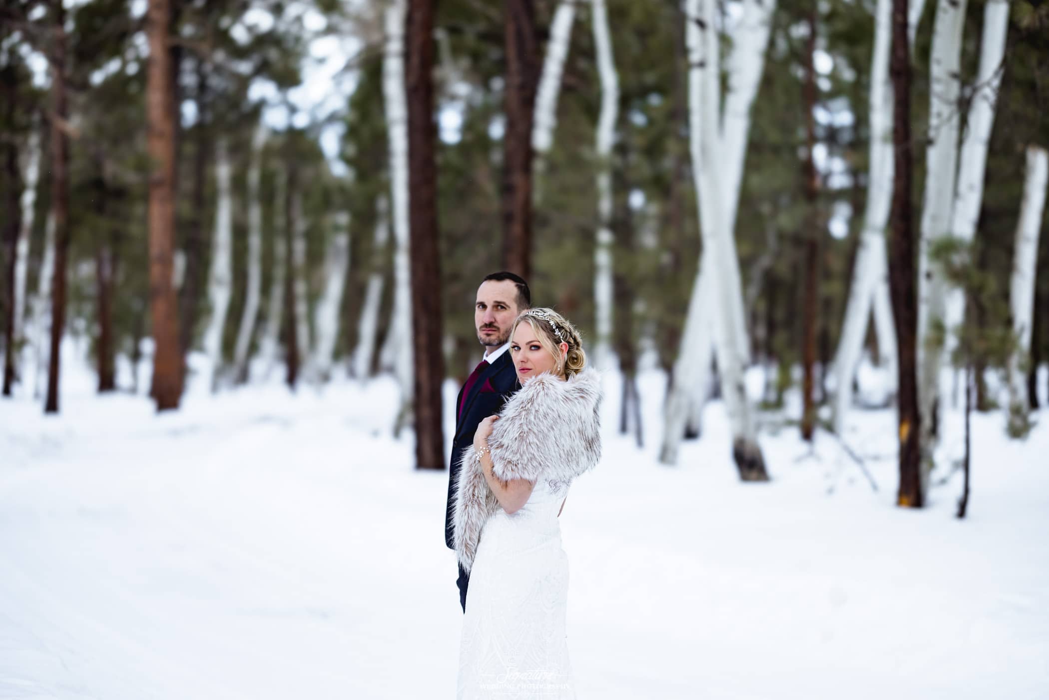Bride and groom looking over shoulder in snow
