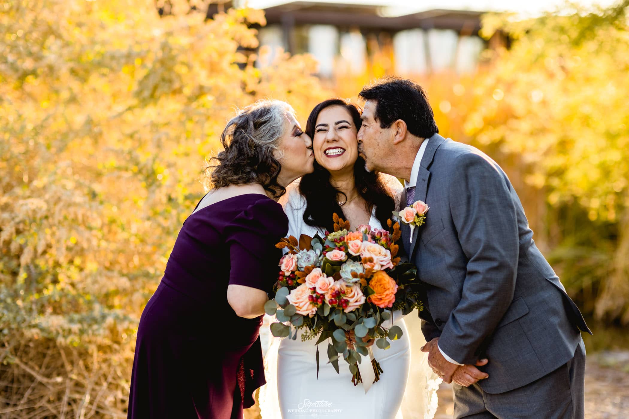 Bride with parents kissing her cheeks