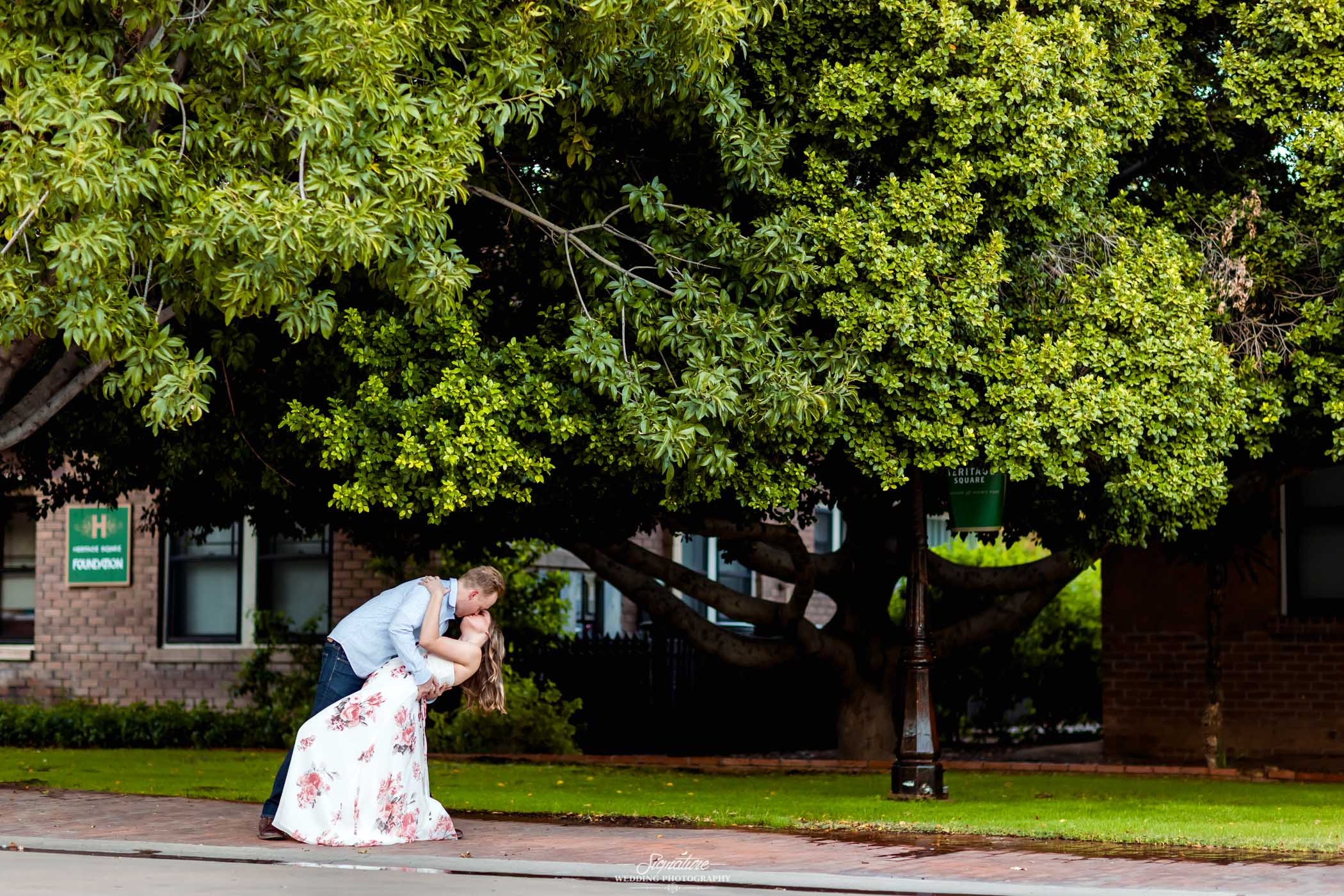 Man dipping woman kissing under tree