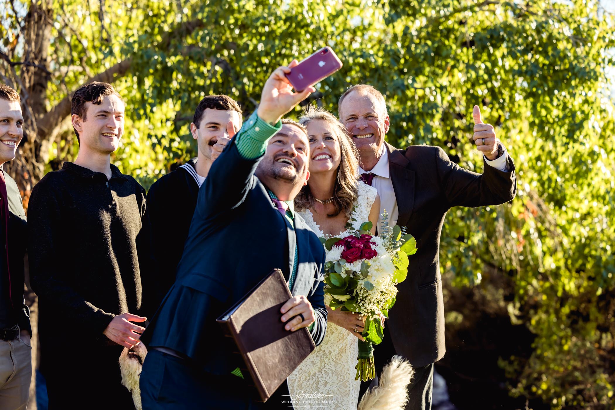 Officiant taking picture with bride and groom on cell phone