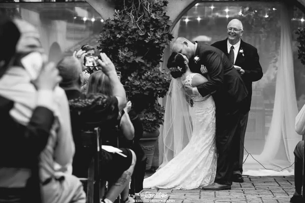 Bride and groom kissing wedding quests taking pictures