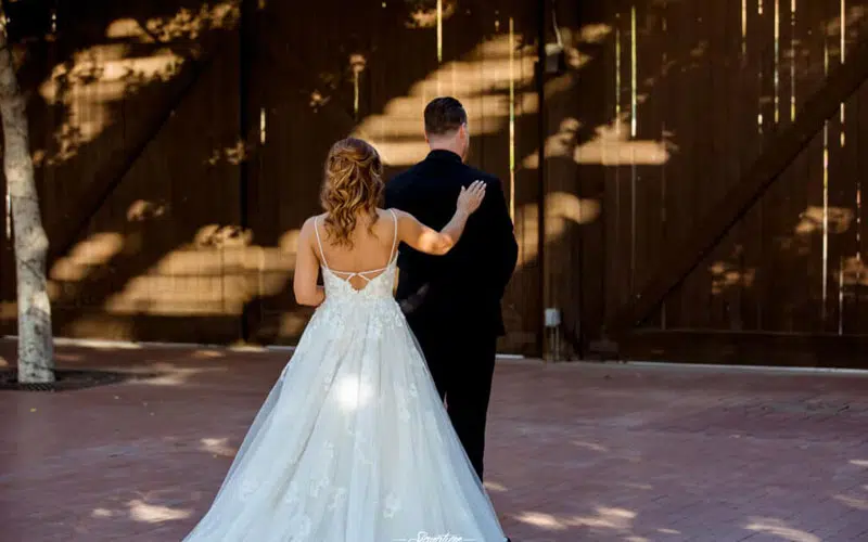 Bride with hand on groom's shoulder for first look