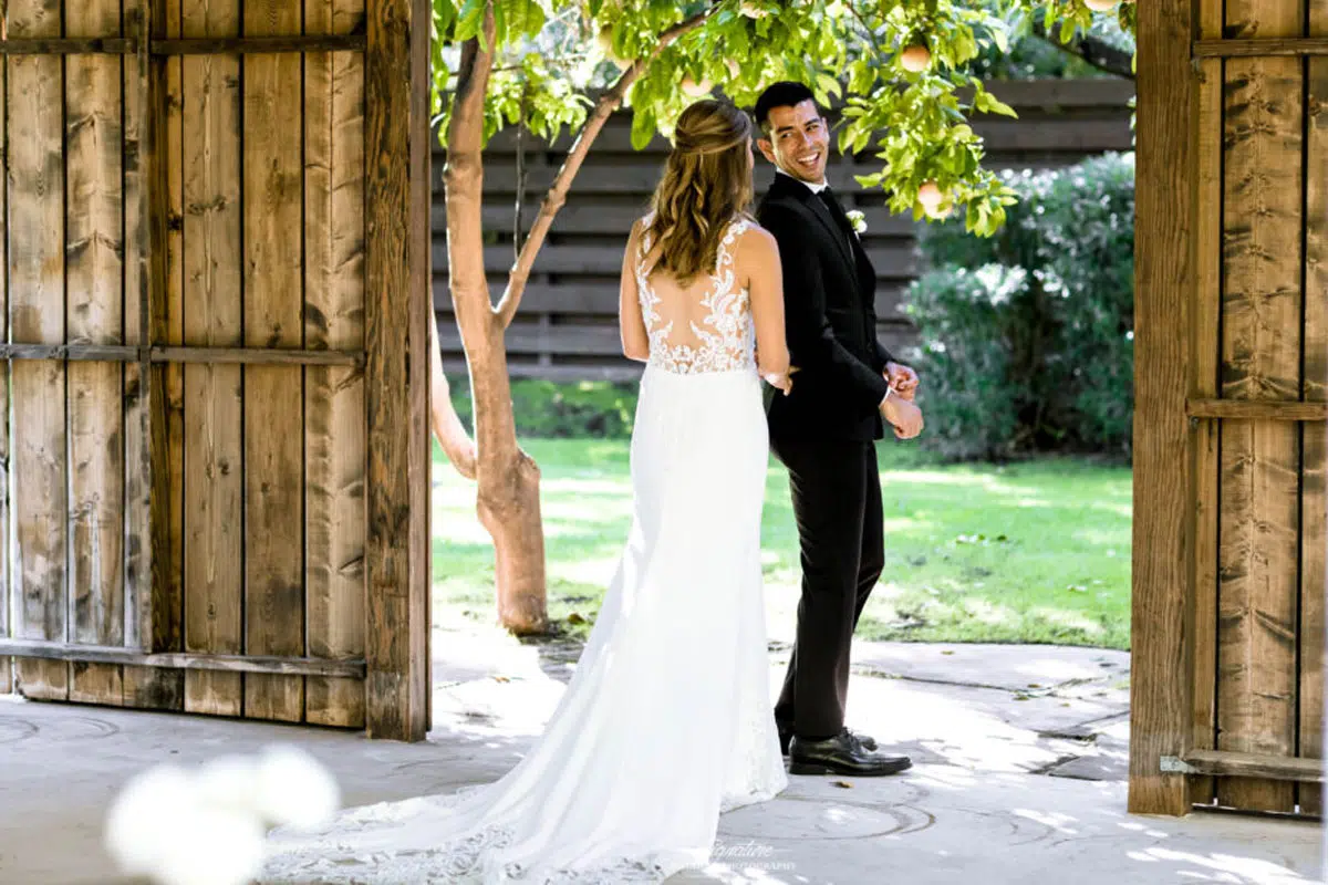 Groom looking over shoulder at bride first look