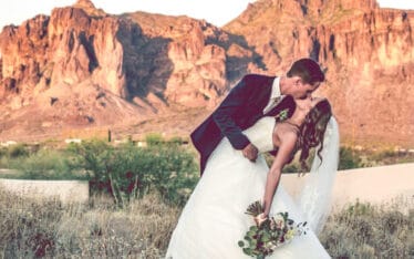 groom kissing bride with mountains in background