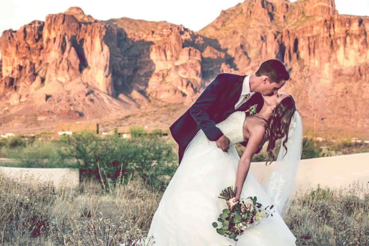 groom kissing bride with mountains in background